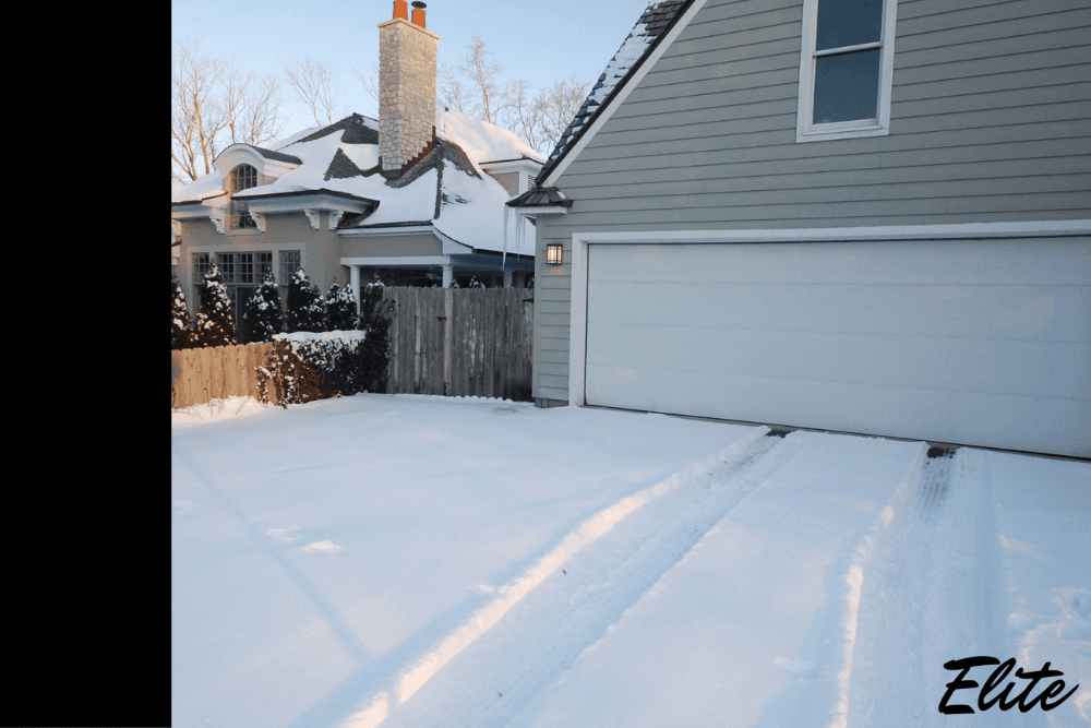 Home driveway covered in snow leading to a closed garage door serviced by Elite Garage Door.