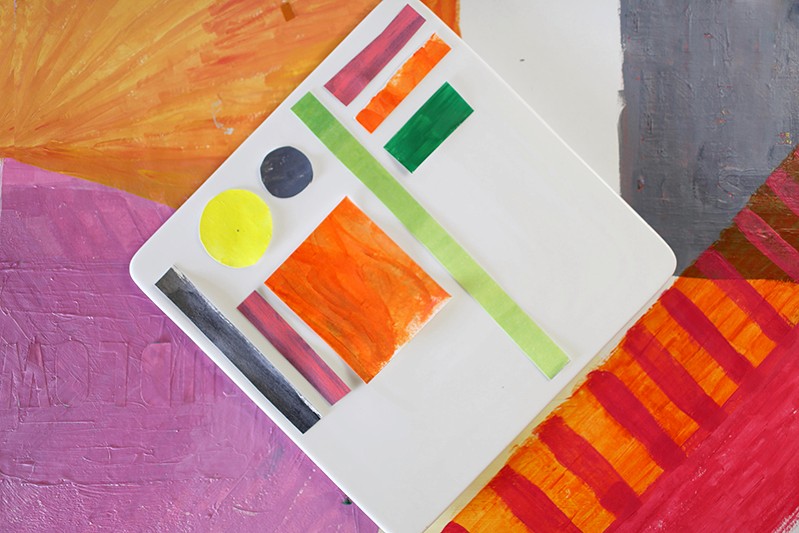 A set of red, orange, green, yellow and indigo shets of paper put on a white plastic pad. Around it there are some orange, red, pink, gray and white papers.