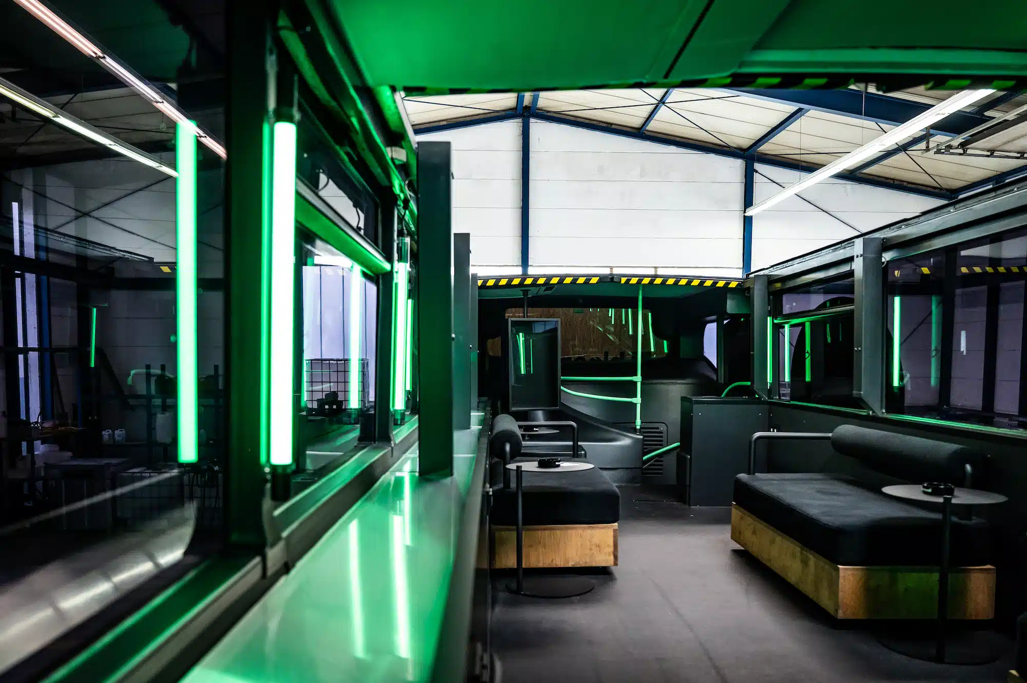 Bloomwell Cannabis App – lounge area on the upper floor of the Bloomwell bus with sofas and green neon ambiance
