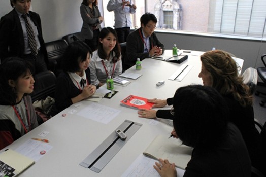 people sitting at a table with pens, rulers, and notepads