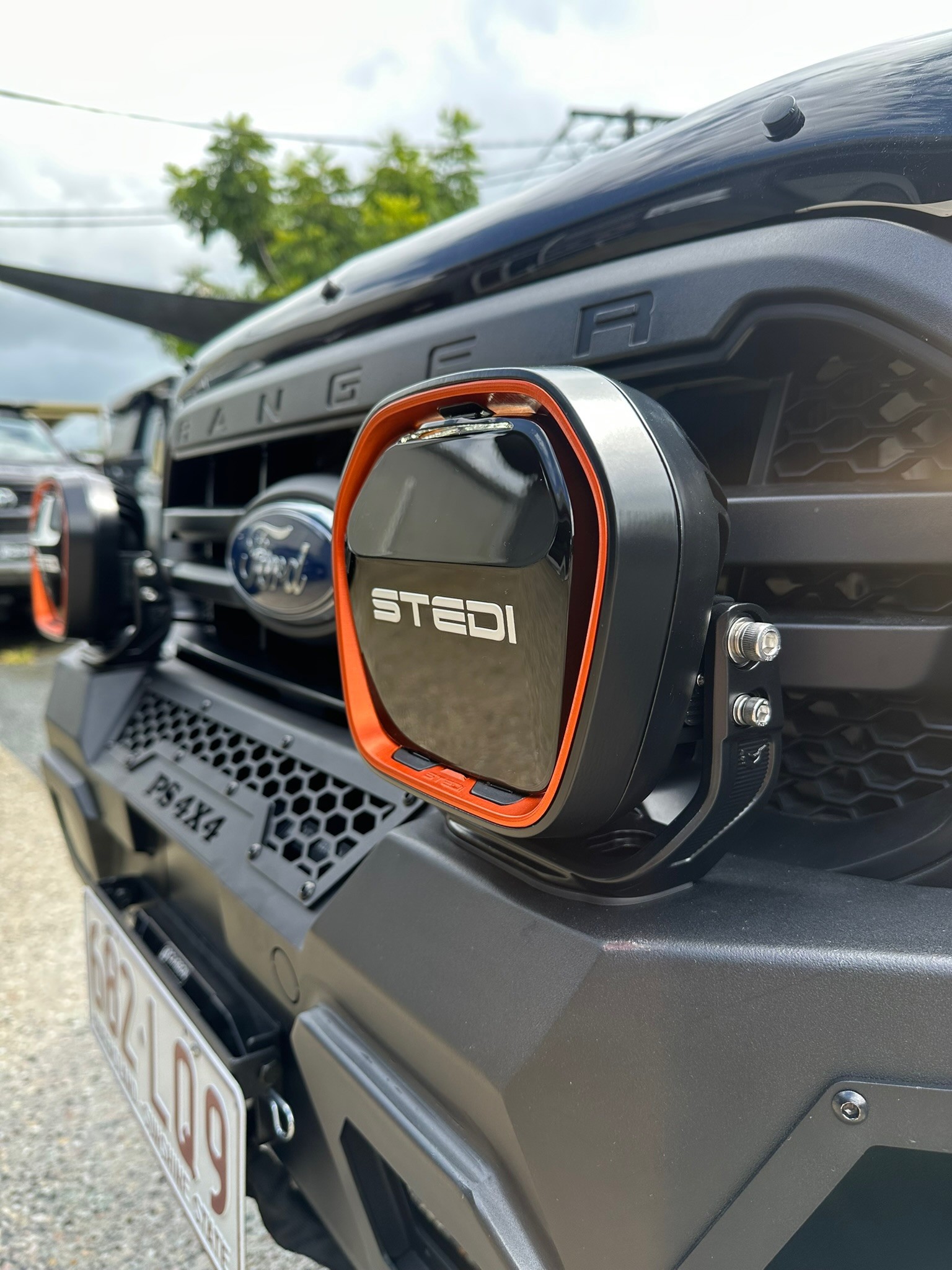 A close-up of a premium STEDI LED driving light with an orange bezel mounted on the bull bar of a Ford Ranger, showcasing professional 4x4 touring lighting installations.