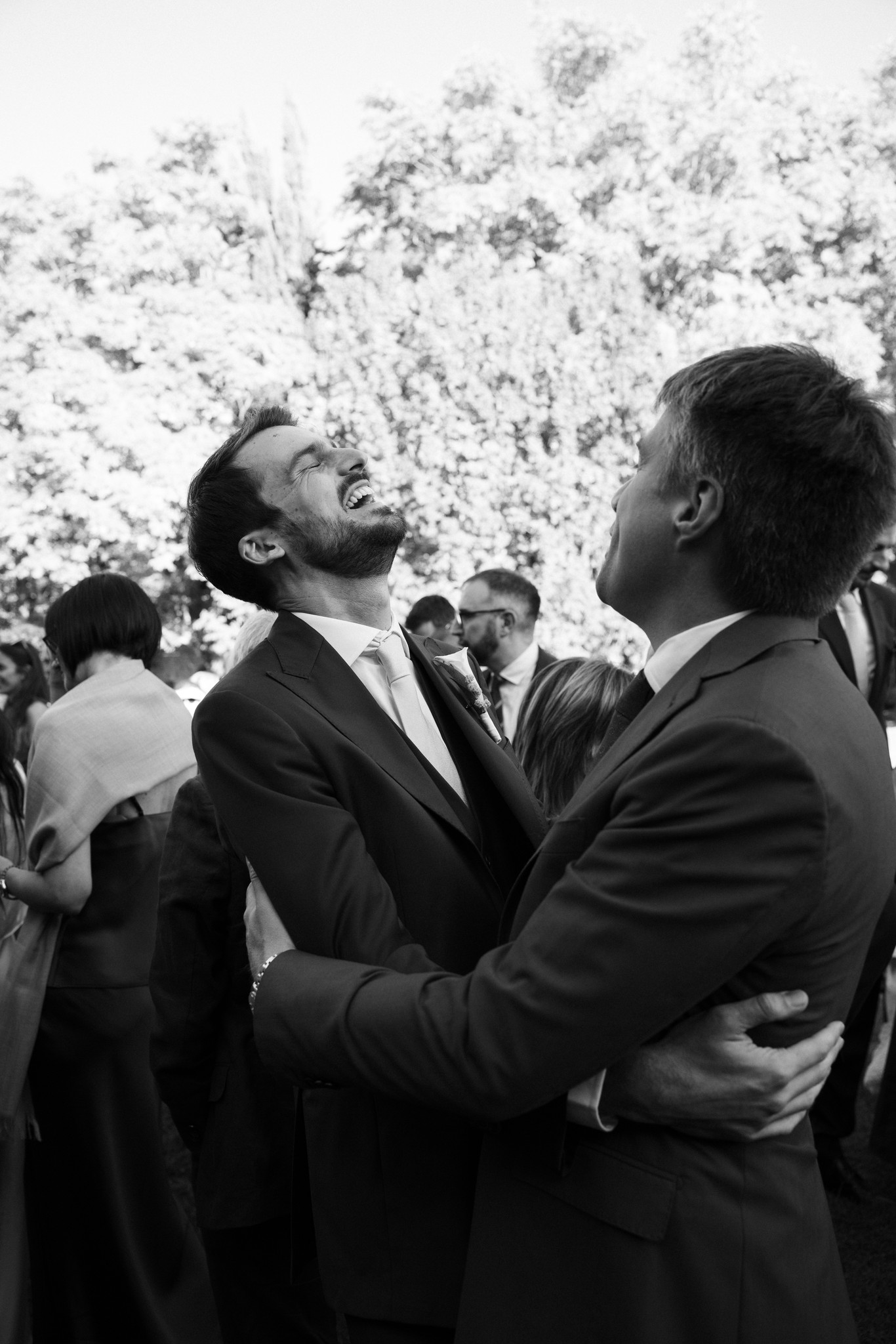 Sposo abbraccia lo sposo durante cerimonia al Castello di Scipione, reportage di matrimonio in bianco e nero