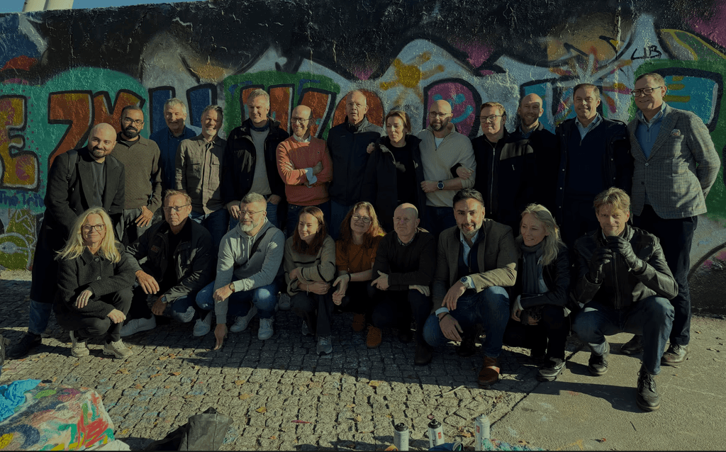 Two men pose inside a workshop.