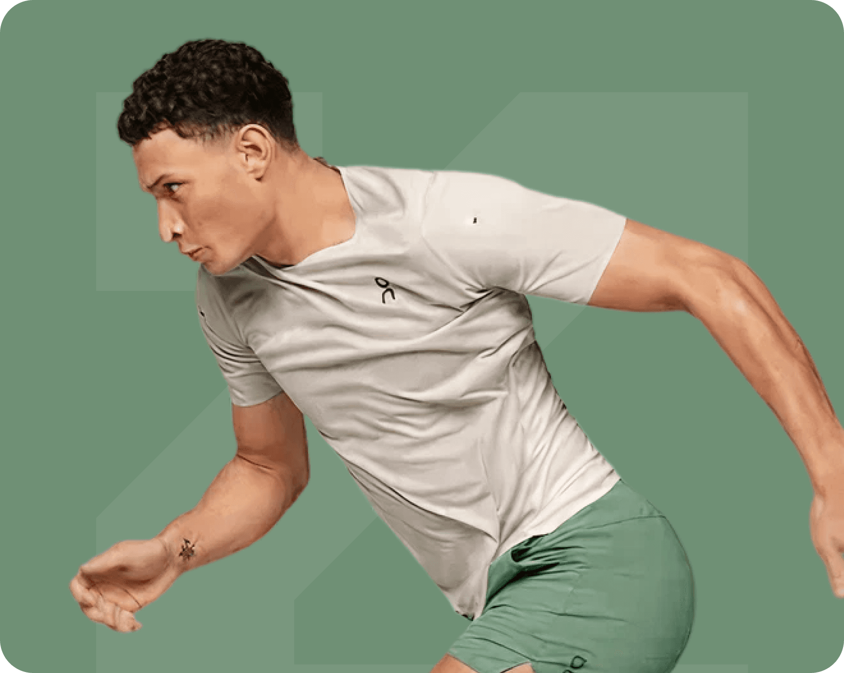 Man in athletic wear running, wearing a light gray t-shirt and green shorts, with arm tattoo.