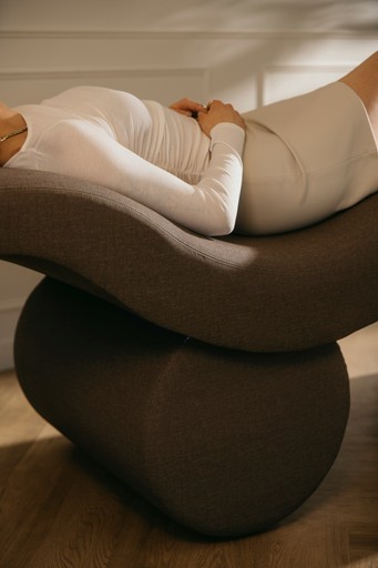 a woman laying on top of a chair on a hard wood floor