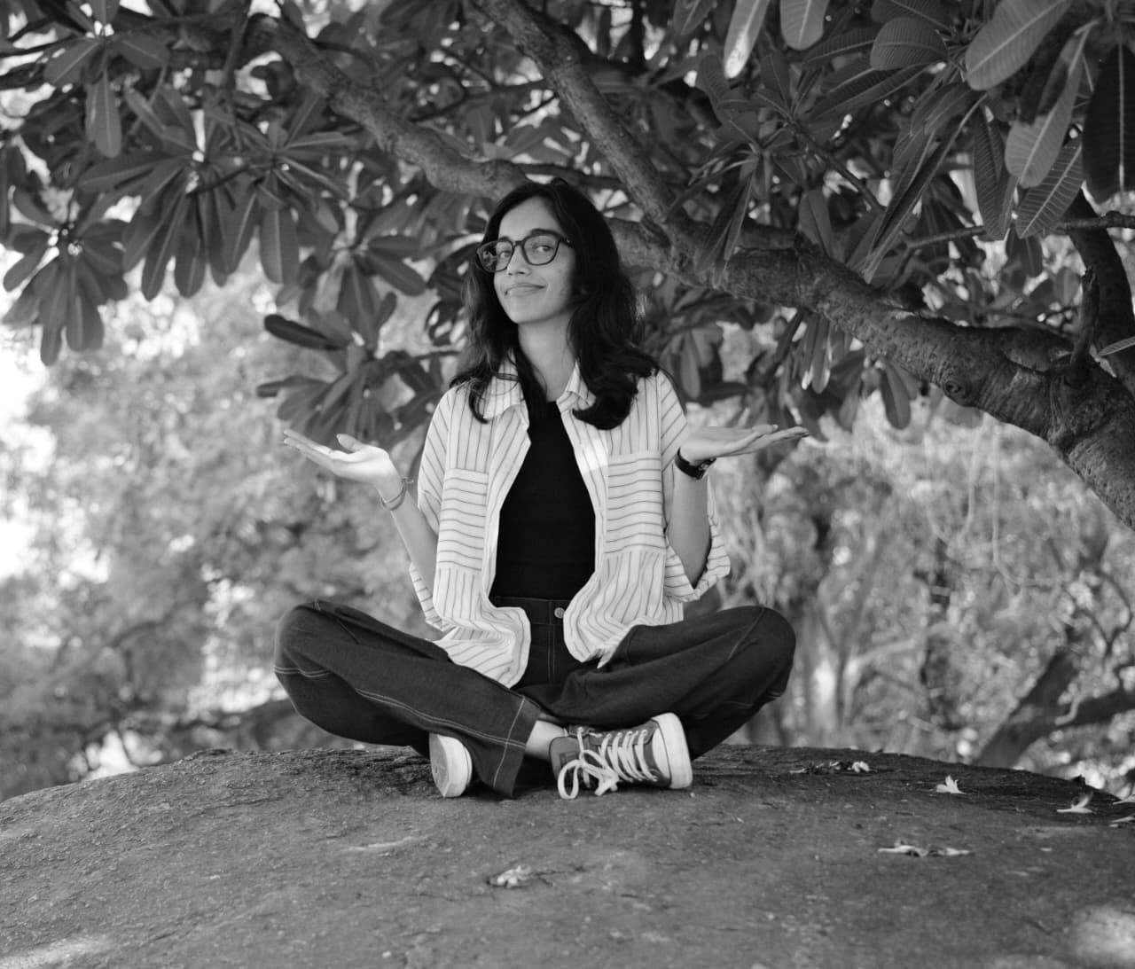 A thoughtful young person with dark hair gazes to the side, captured in soft black and white lighting.