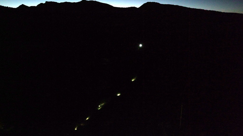 Headlamps snaking up the mountain above town