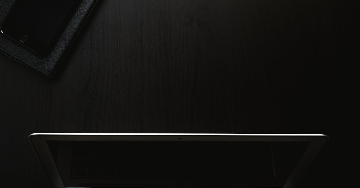 A sleek and minimalist workspace featuring a laptop and smartphone on a dark surface.