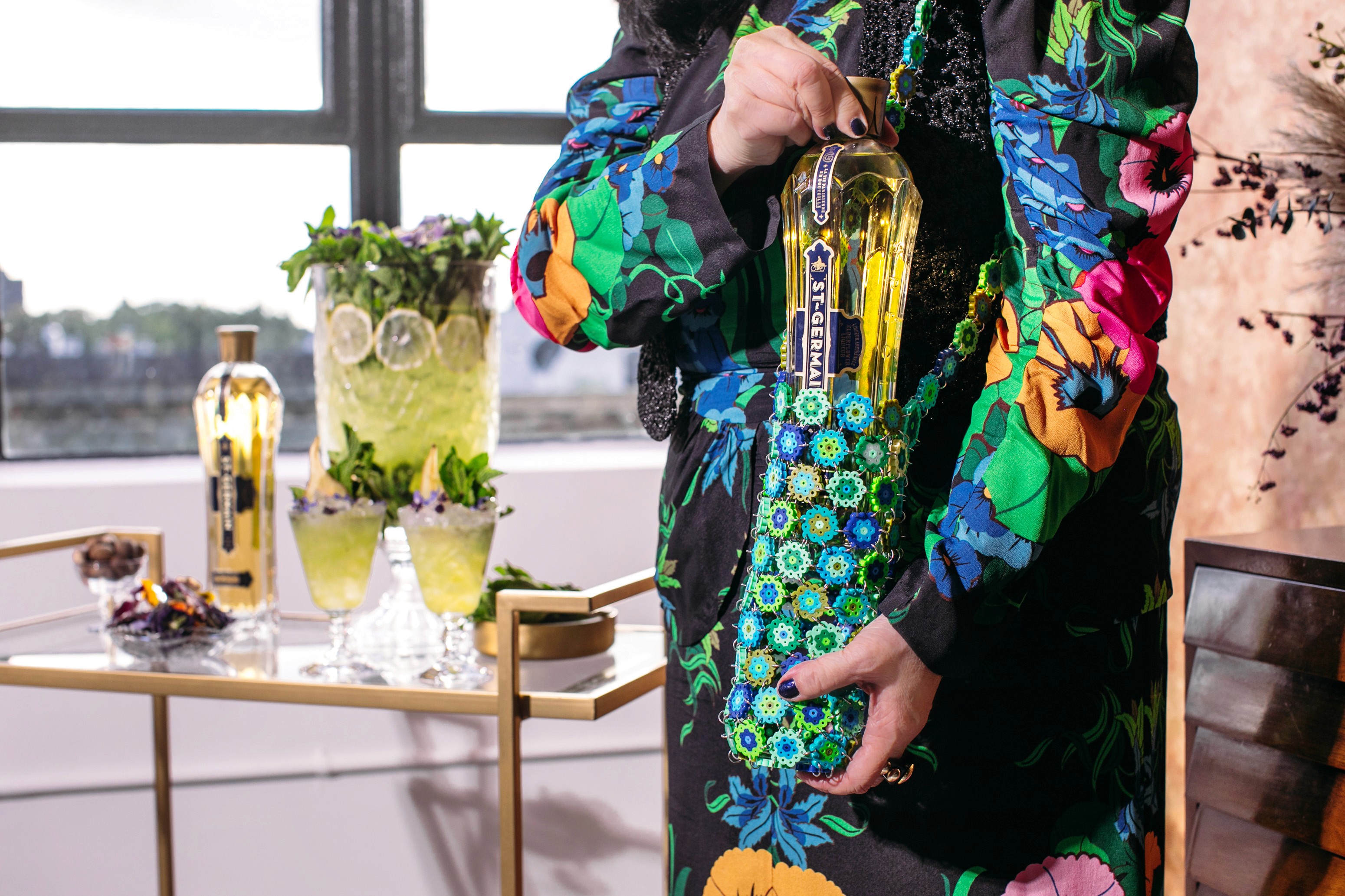 Anna Sui holding the St-Germain bottle in its limited-edition floral tote