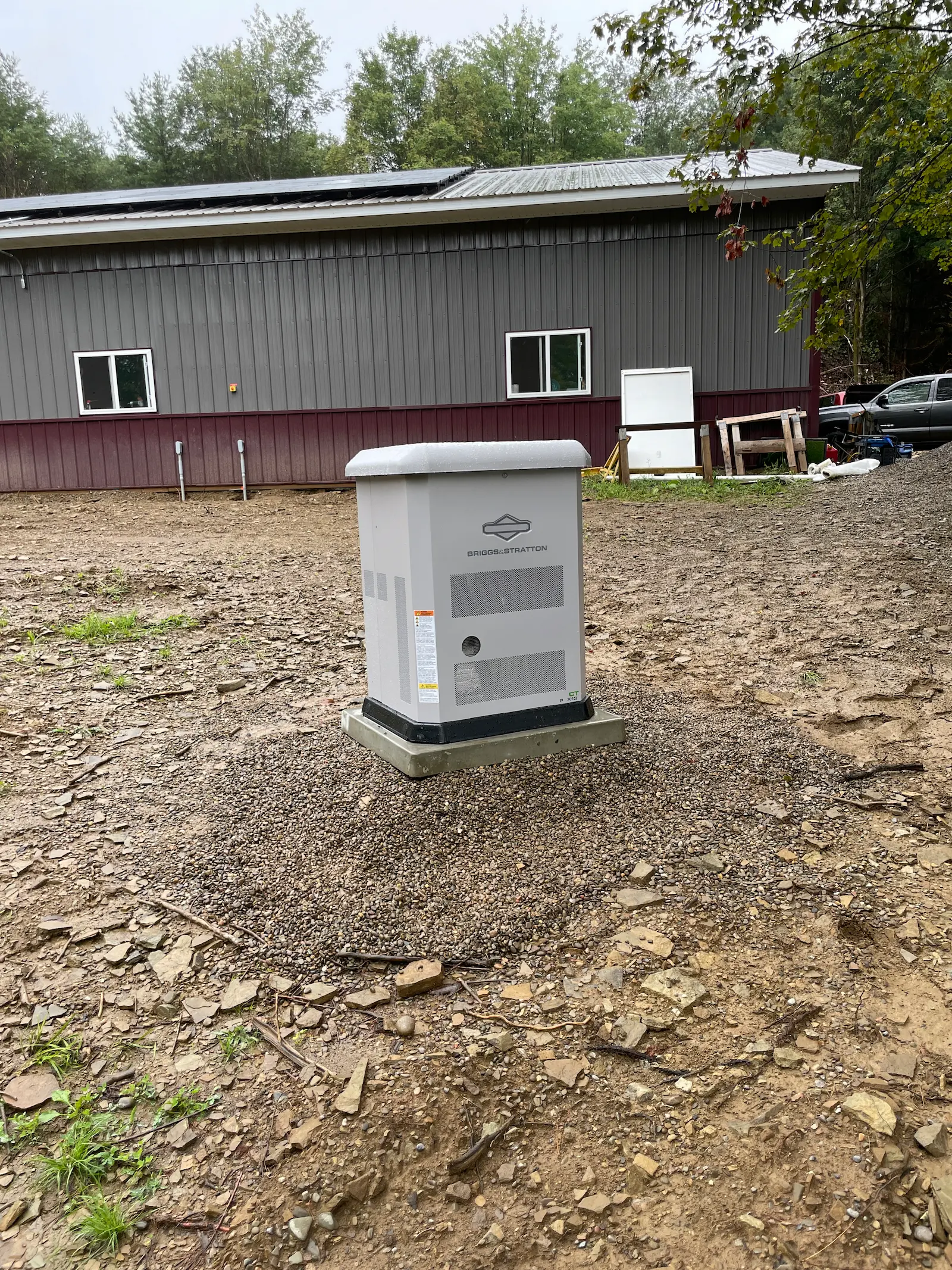 Briggs & Stratton standby generator installed outside a metal-sided building on a gravel pad.