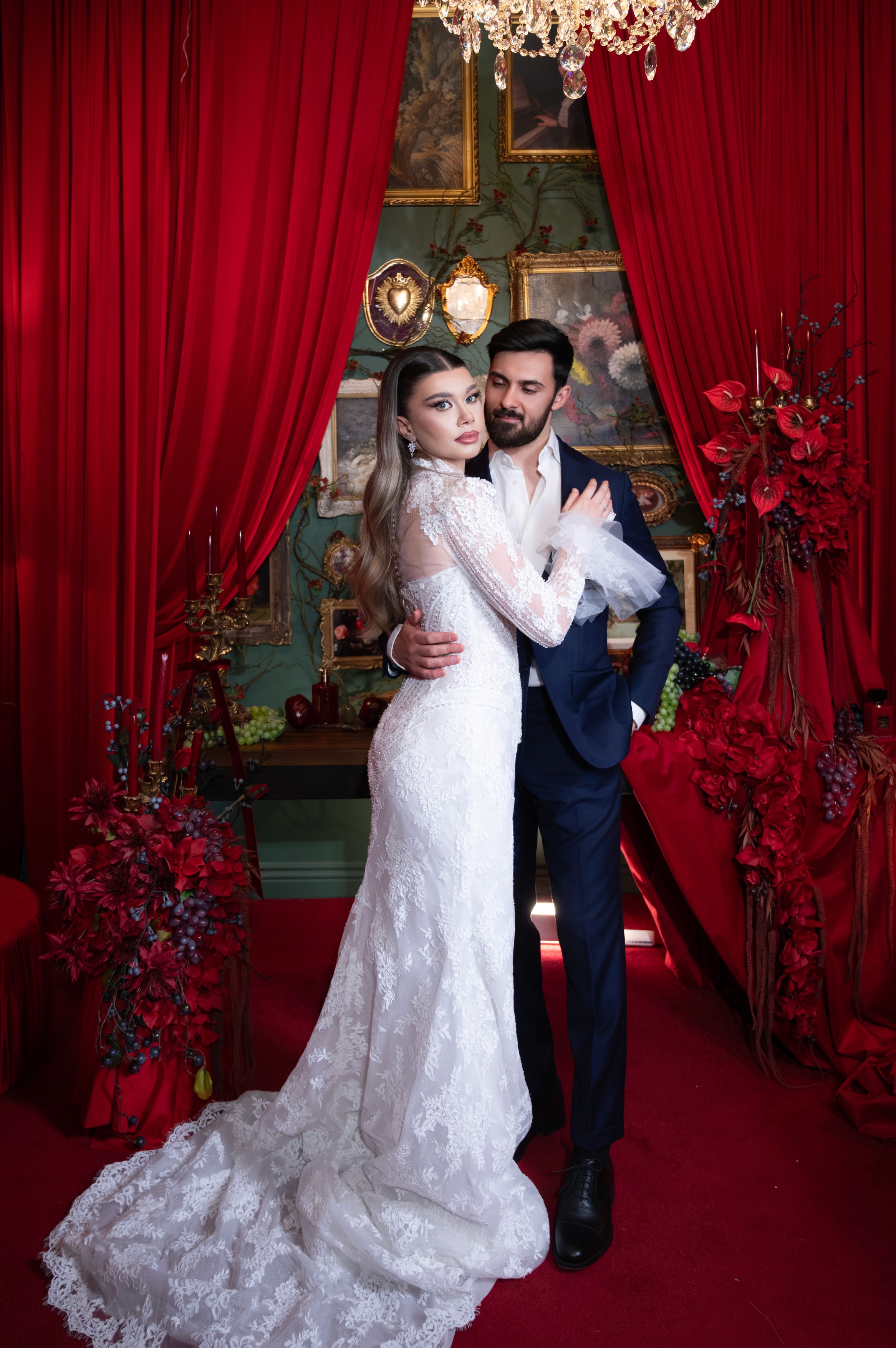 Mire și mireasă fotografiați full body într-un decor dramatic cu draperii roșii, fotografie de nuntă în București