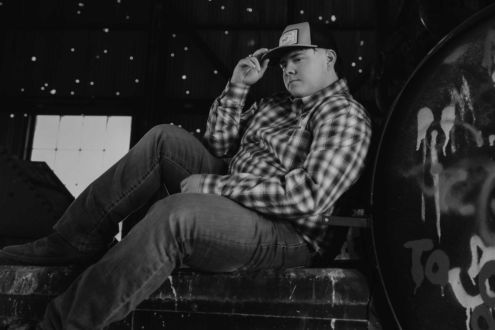 A man sits firm while gripping his hat.