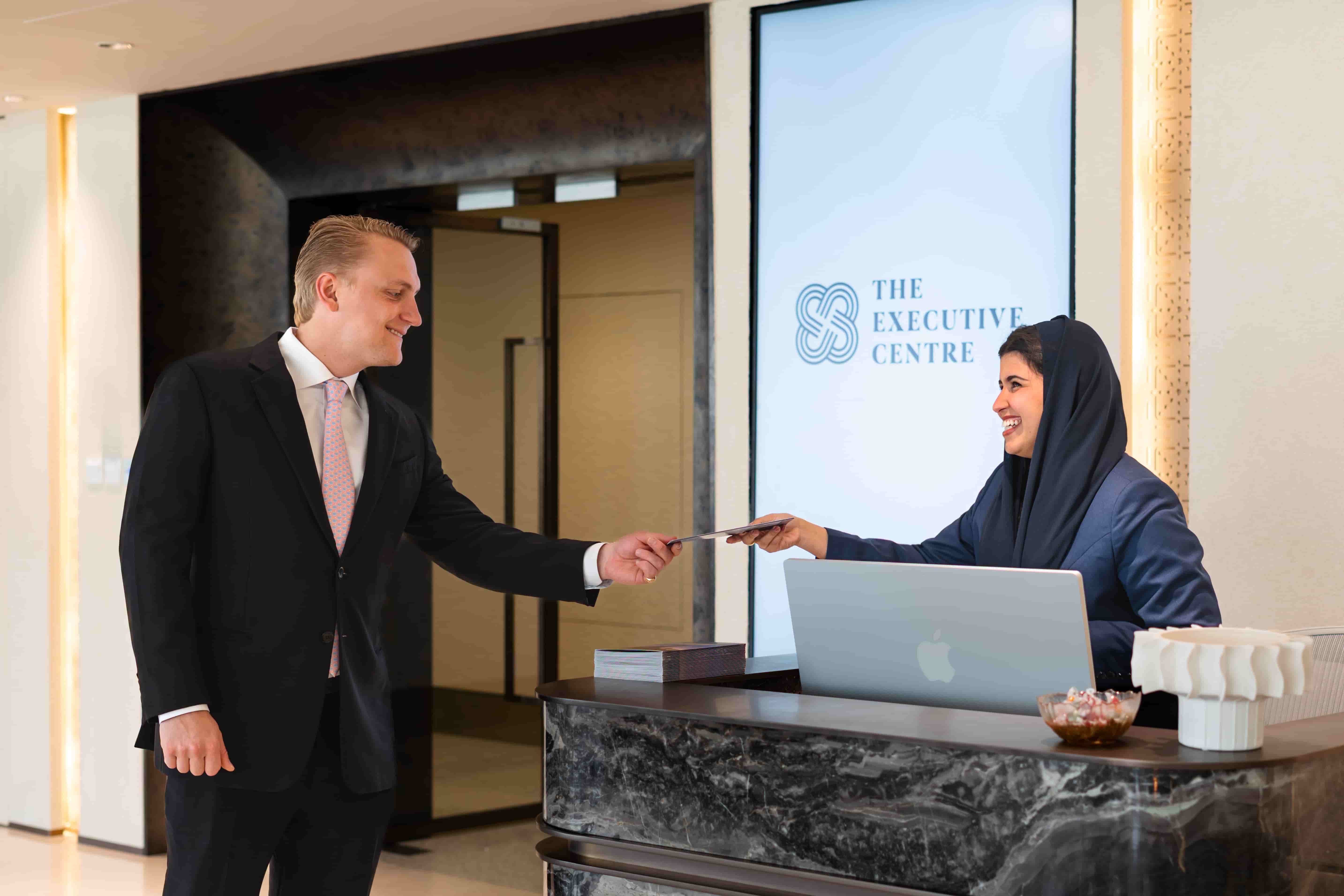 Business professional receiving an access card from a receptionist in Riyadh’s The Executive Centre reception desk
