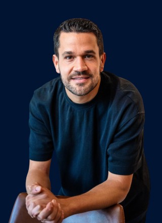 Close-up of a dark green leaf showing its textured surface and central vein against a muted background.