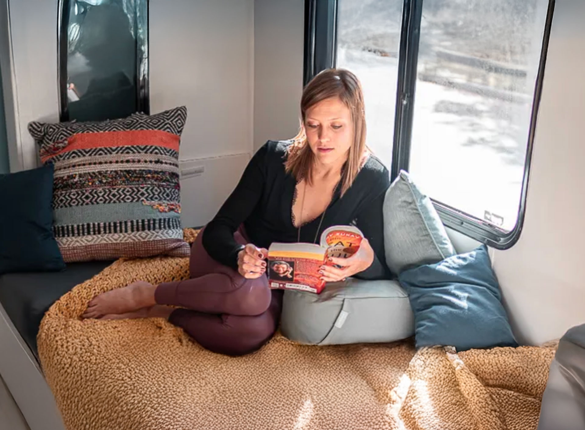 Bre sat by a sunlit window reading a book.