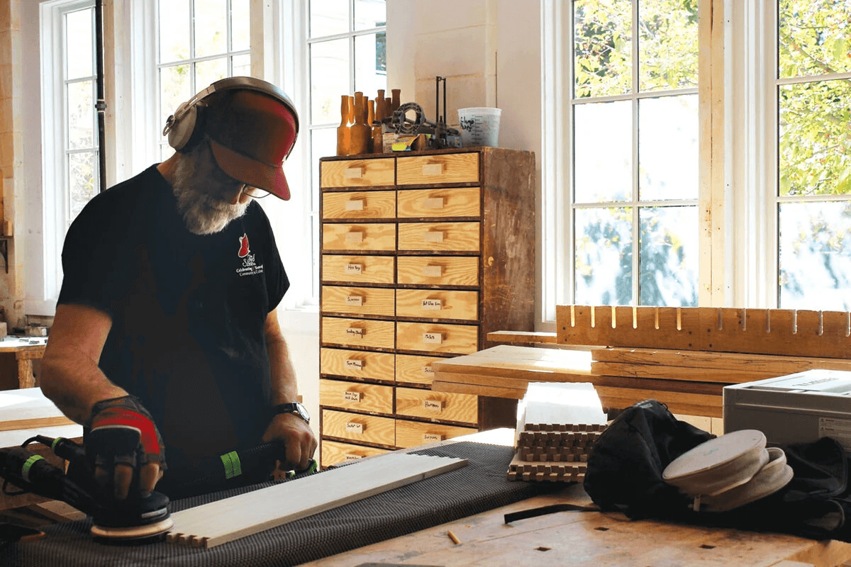 Mike Goglia, a resident woodworker with the Shelburne Craft School, sands down a large project in the school’s woodworking space. The craft school is marking its 80th year.