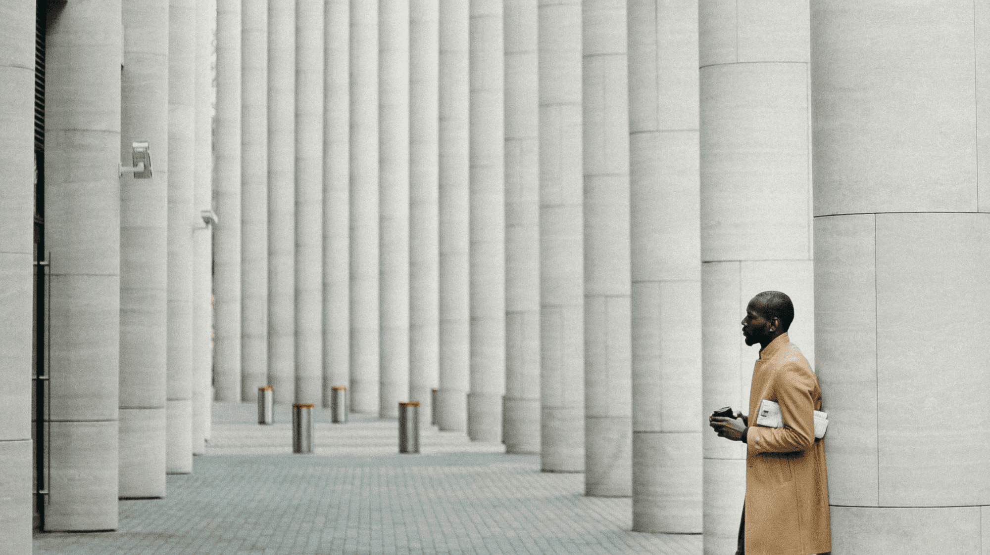 A man standing on the side of a street while talking on a cell phone