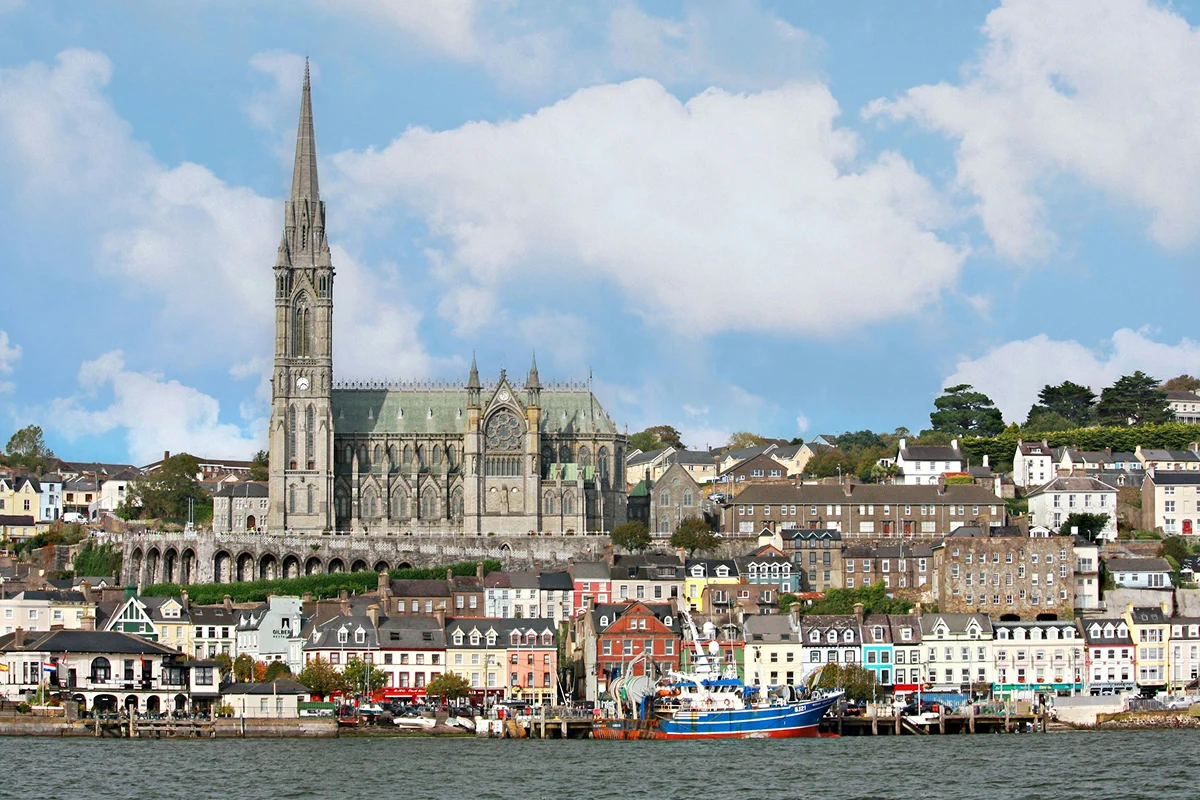 Waterfront buildings and a church spire overlooking an Irish harbor.