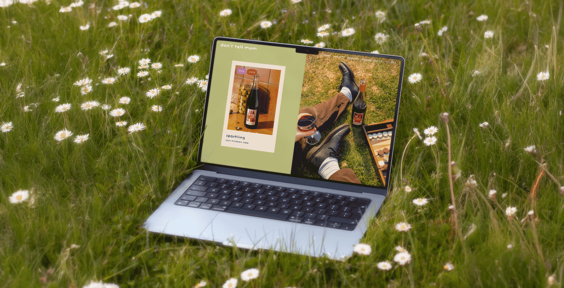 'Don't Tell Mum' website displayed on a laptop sitting in a field of flowers.