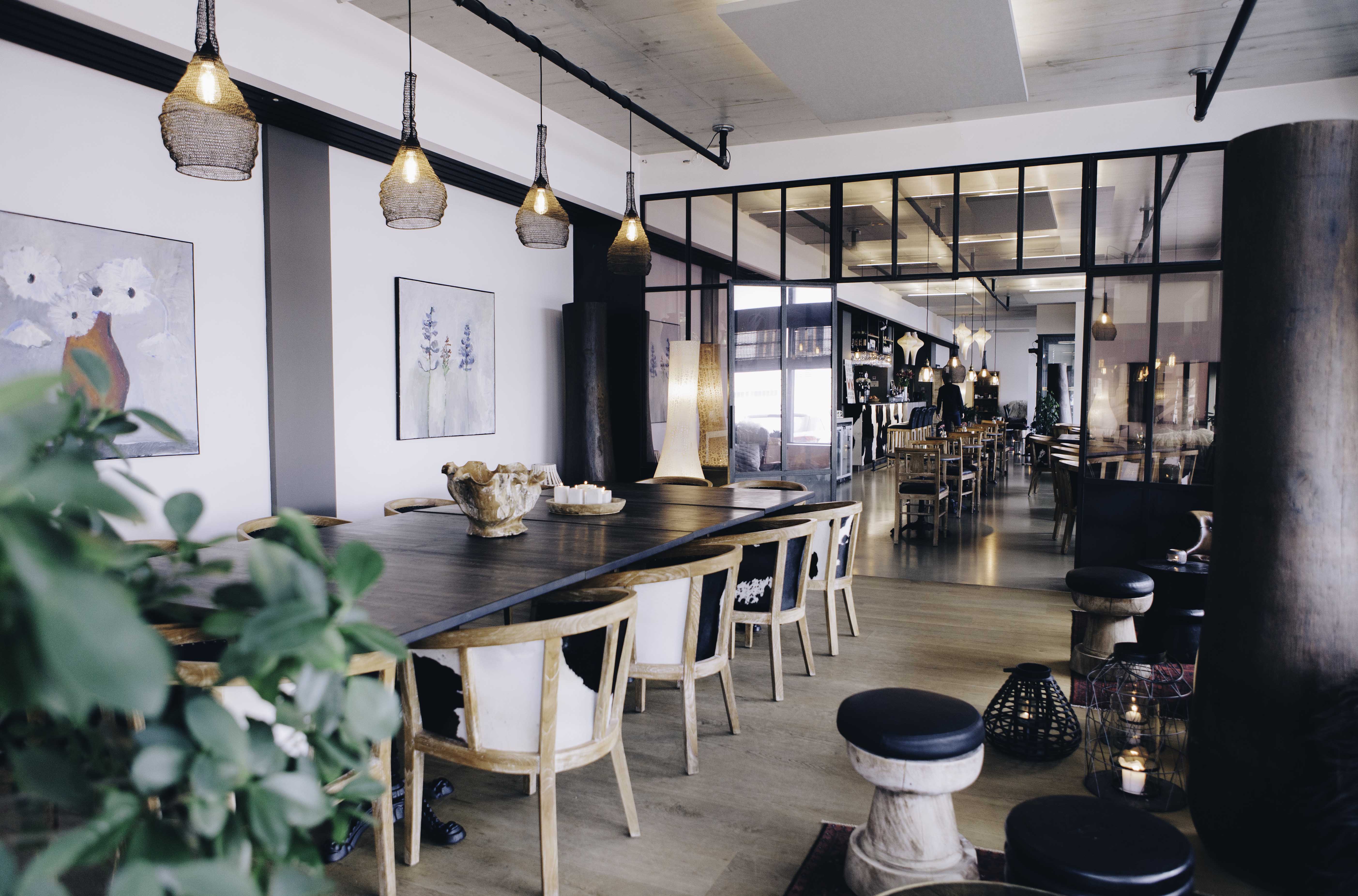 Modern hotel restaurant interior with wooden tables, hanging pendant lights, and a bright open layout