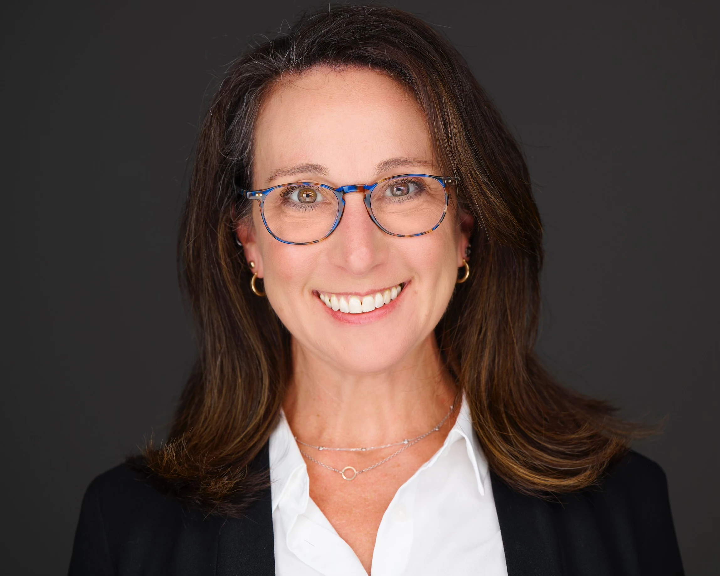 Headshot of Dr. Erica Kesselman with a white shirt, blazer, and blue glasses
