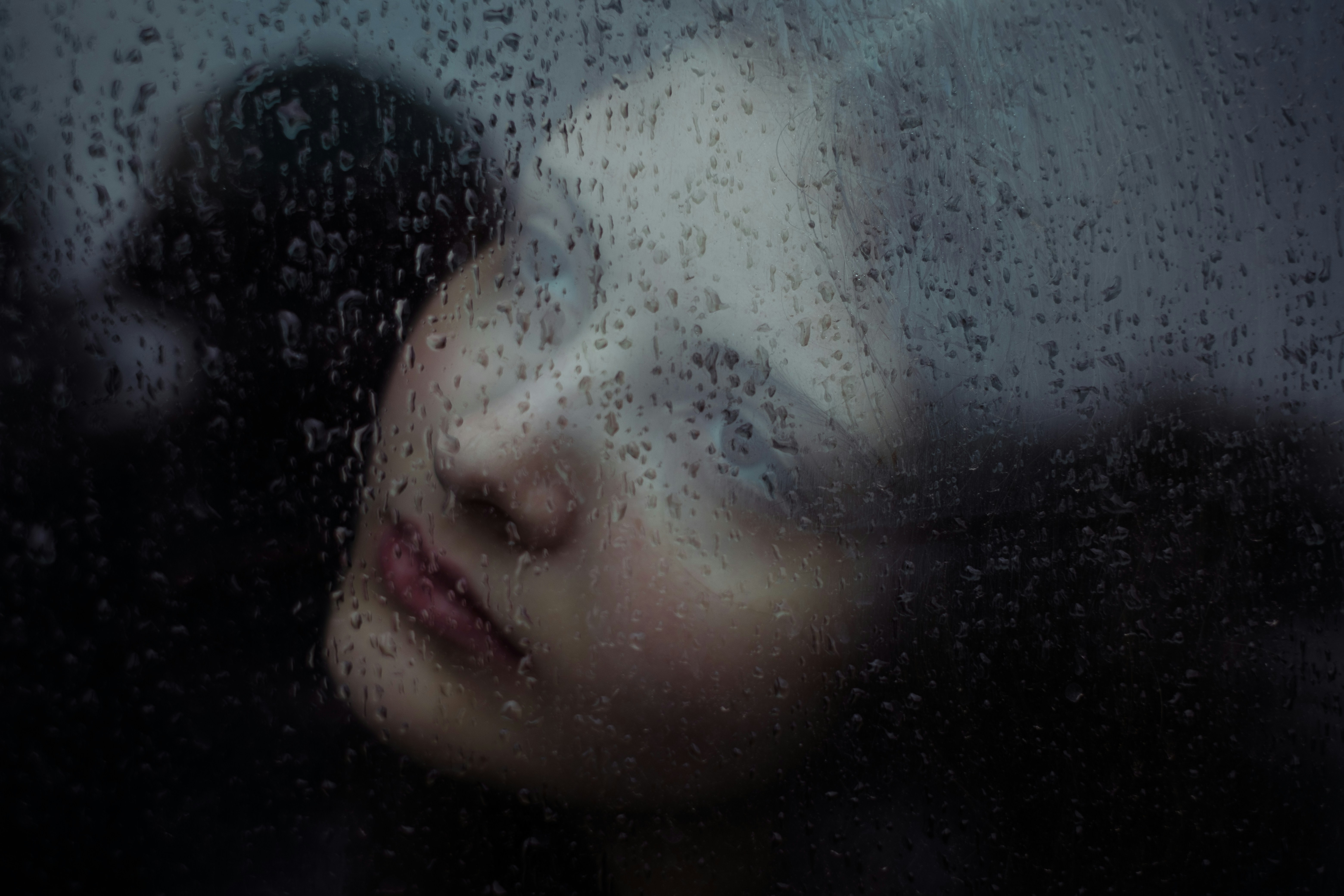 Woman's face seen through rain-streaked glass