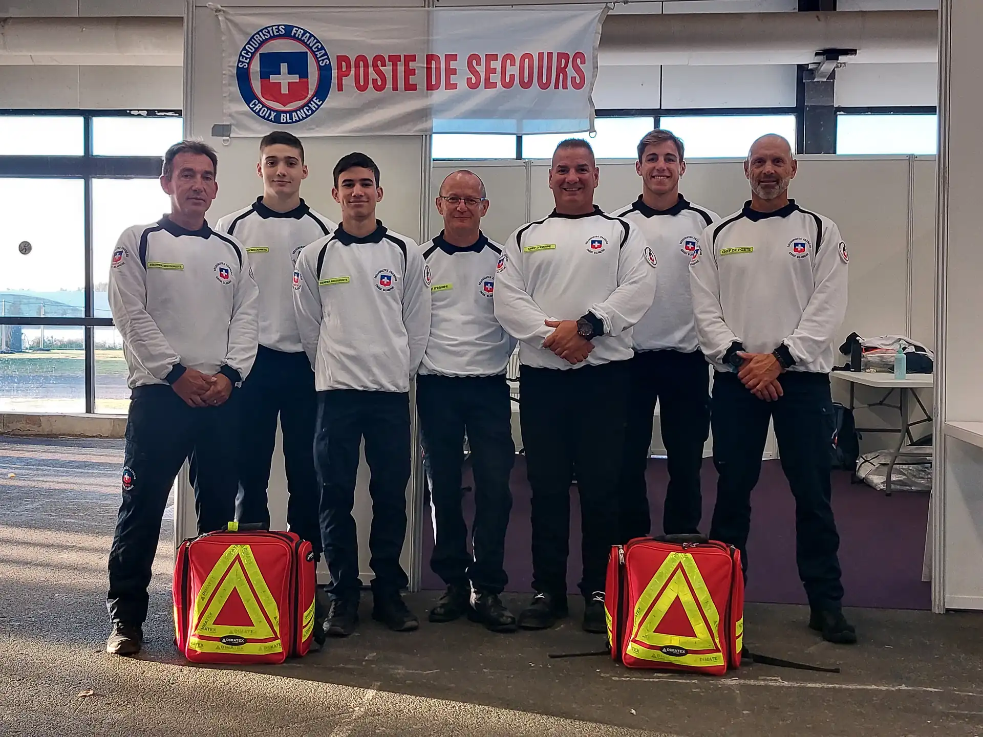Équipe de secouristes français devant un poste de secours avec sacs d'intervention.