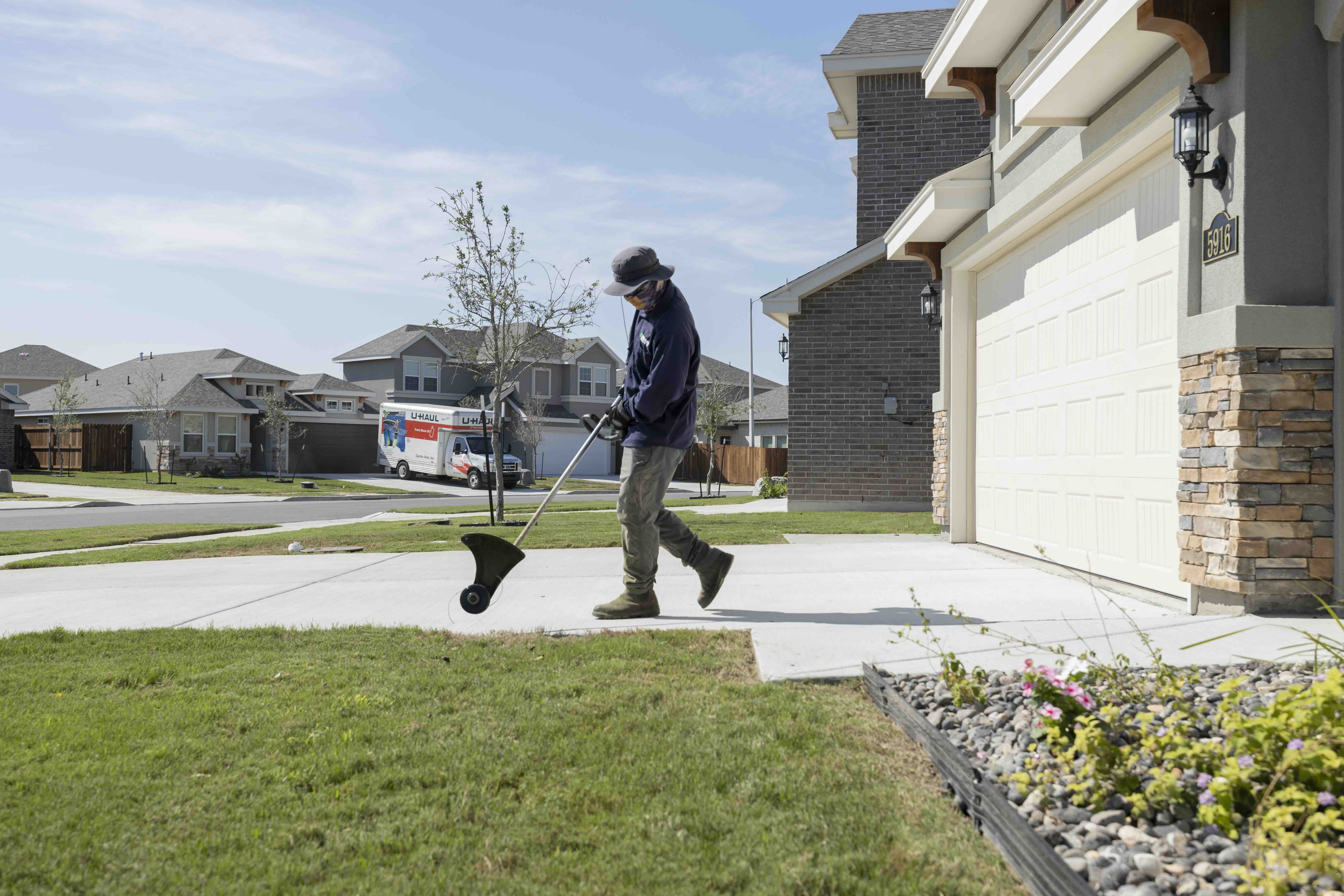 Property maintance worker maintaining yard at Rhodes Enterprises master-planned community new construction neighborhood South Texas