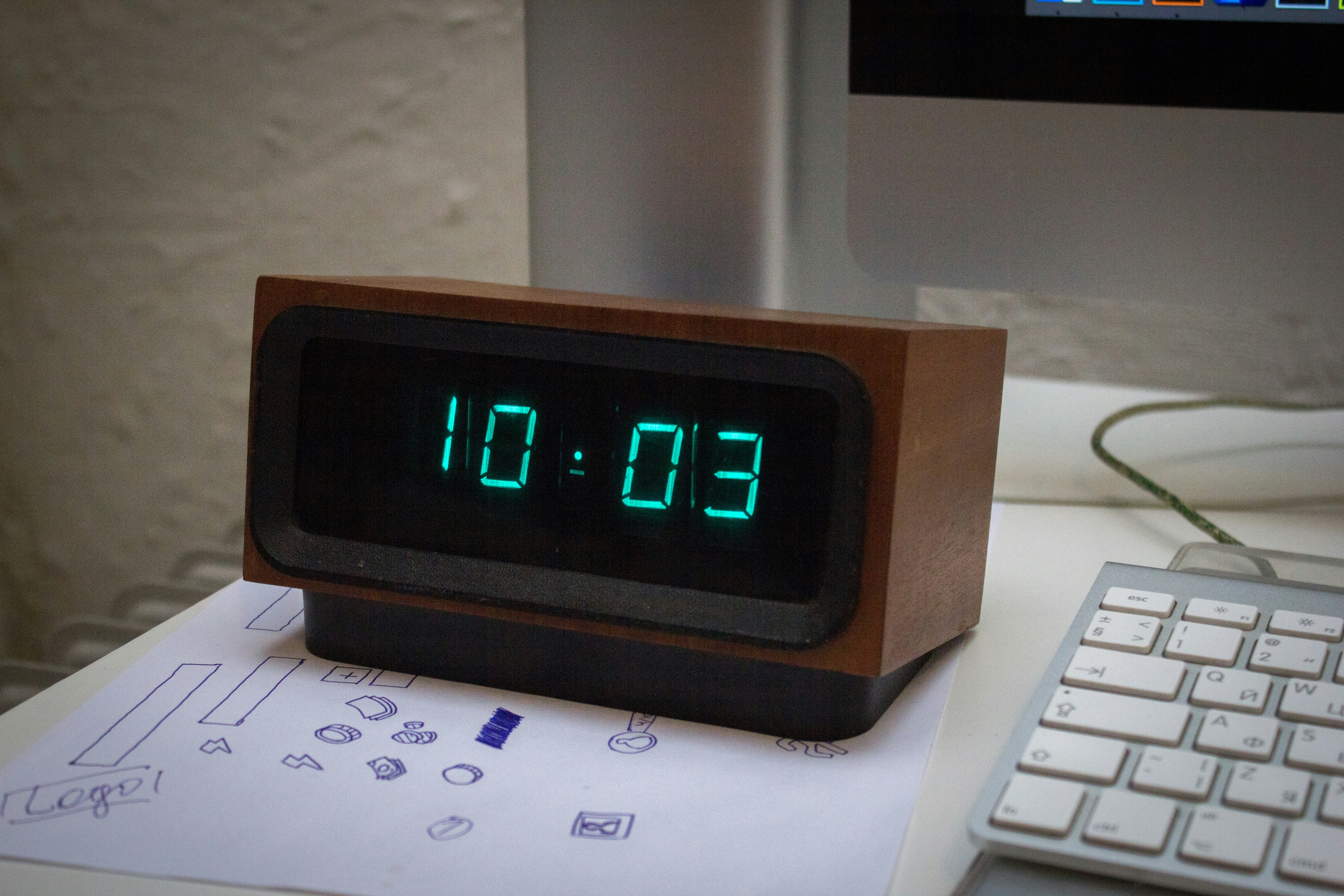 Digital clock on a desk near a computer keyboard.