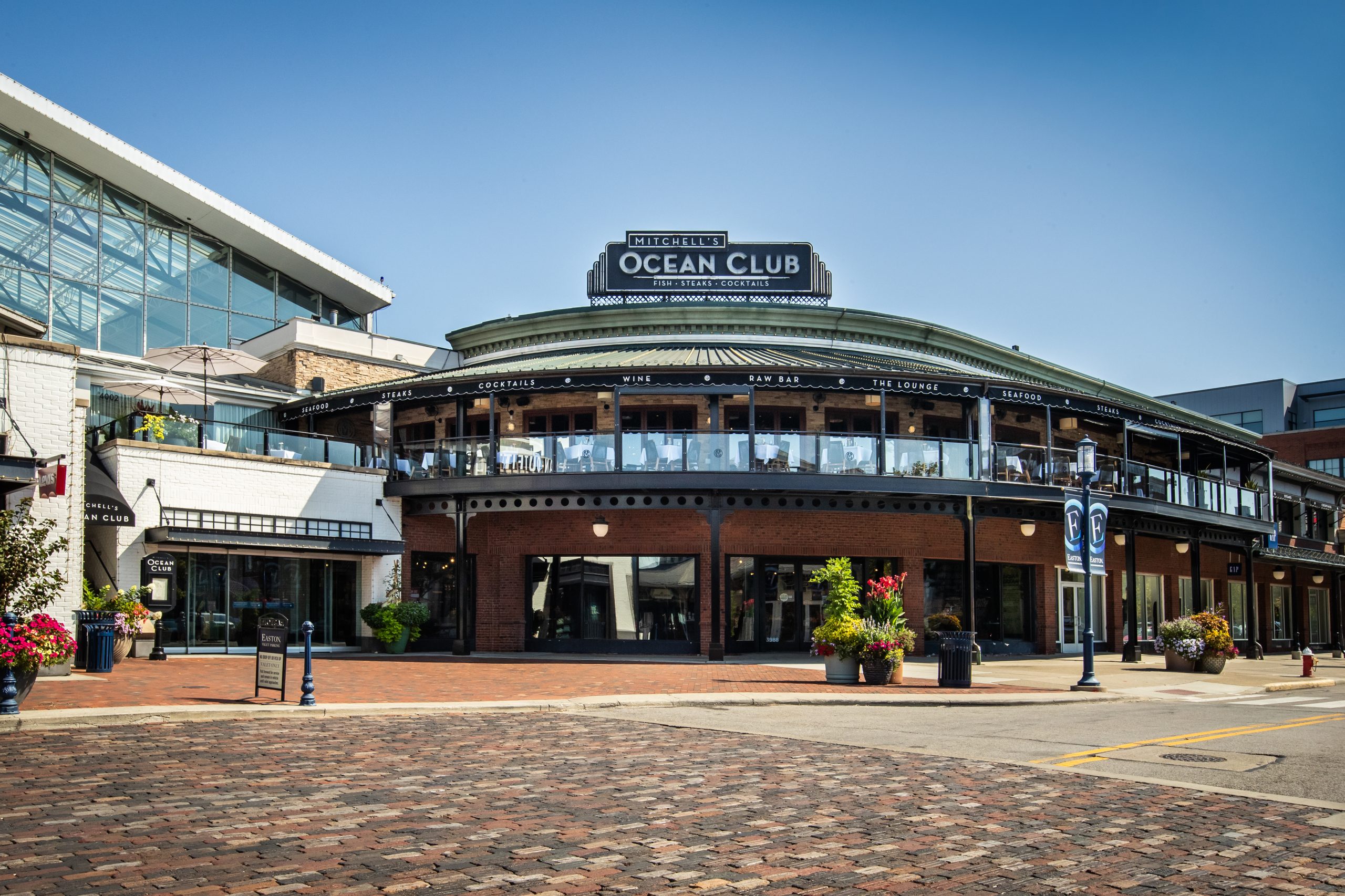 Rounded building with an Ocean Club sign above a brick plaza at Mitchell's Ocean Club