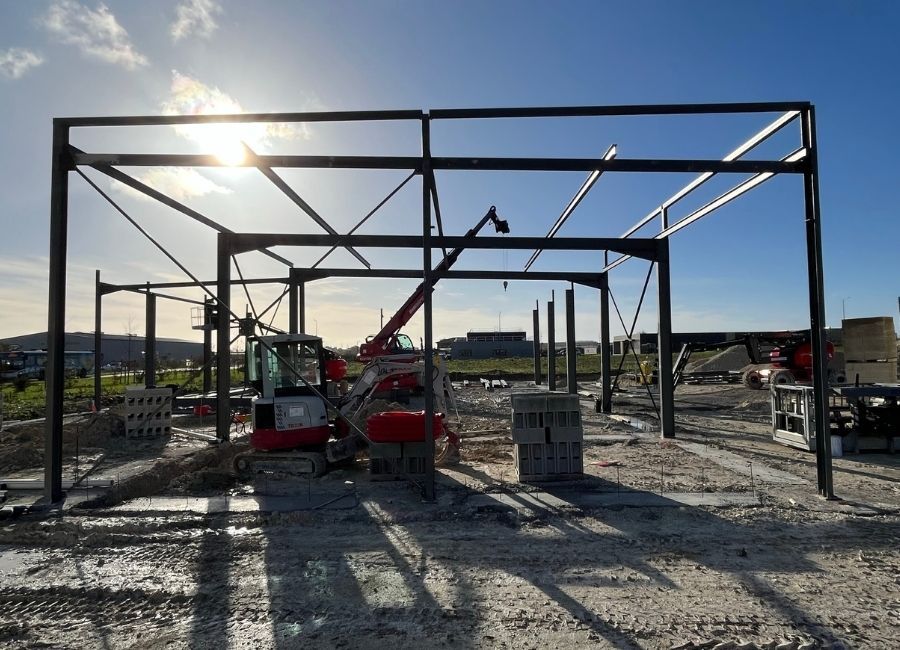 Début de montage d’une ossature métallique sur un chantier de bâtiment industriel.