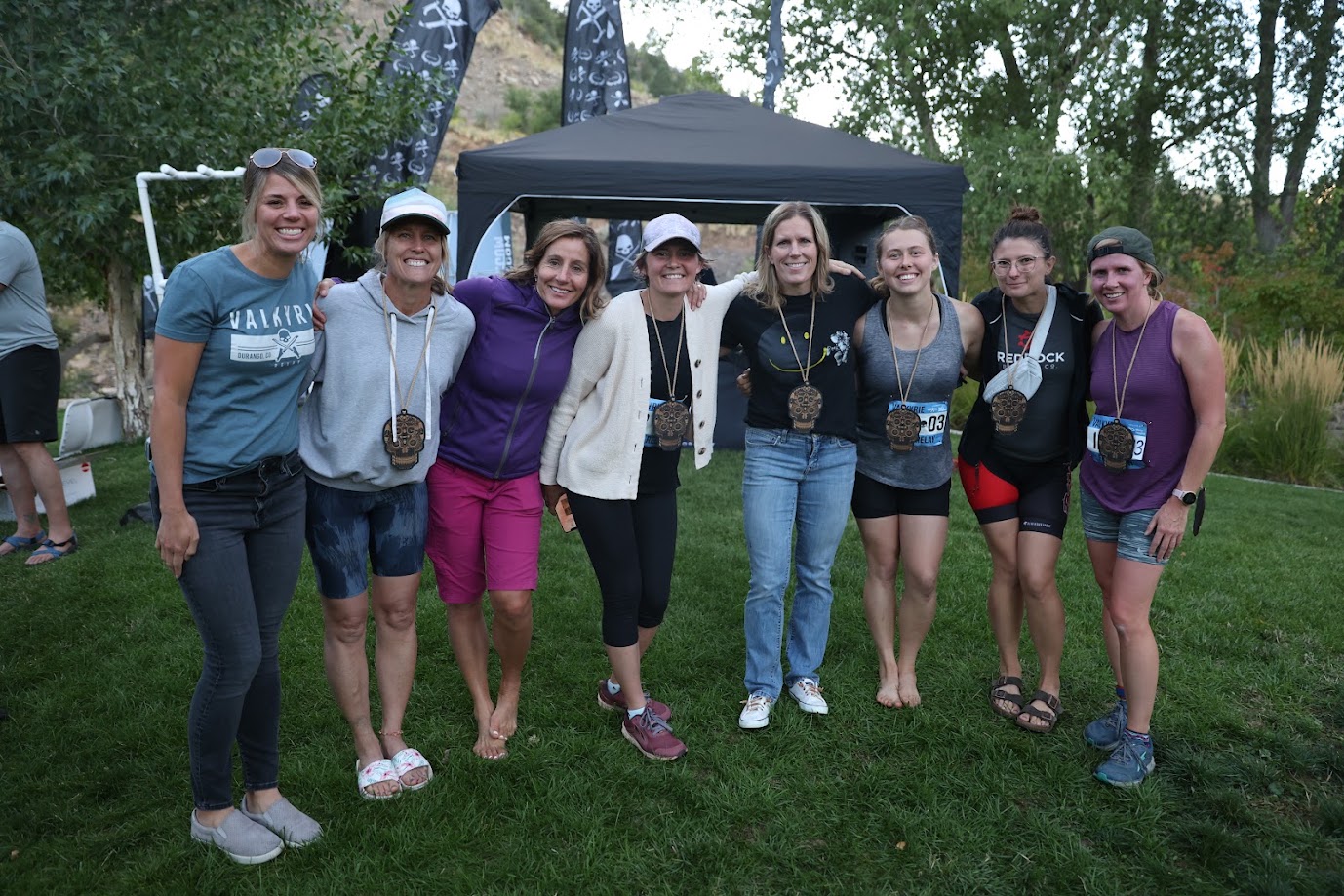 Teammates smiling together in front of a canopy tent