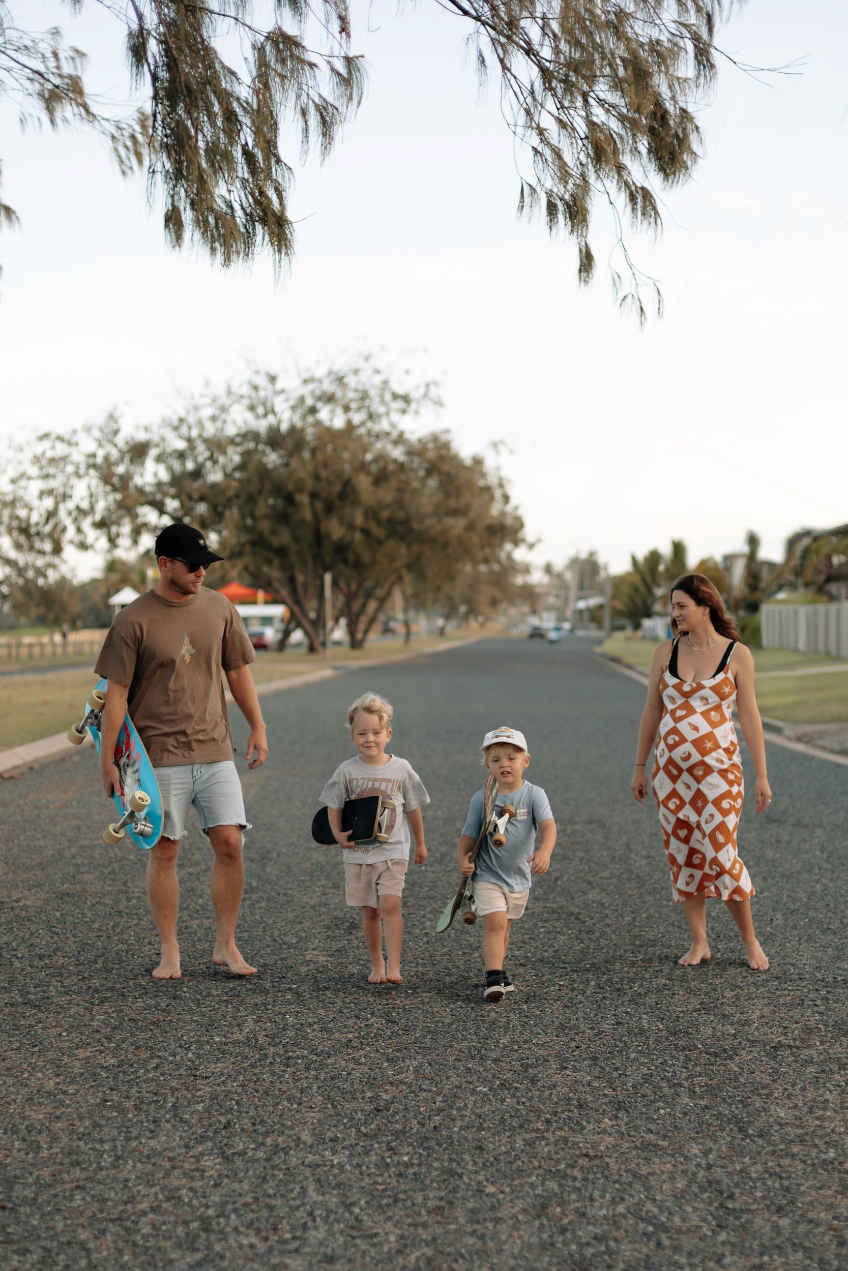 Parents and children walking side by side on a quiet street during a lifestyle family photography session in Mackay.