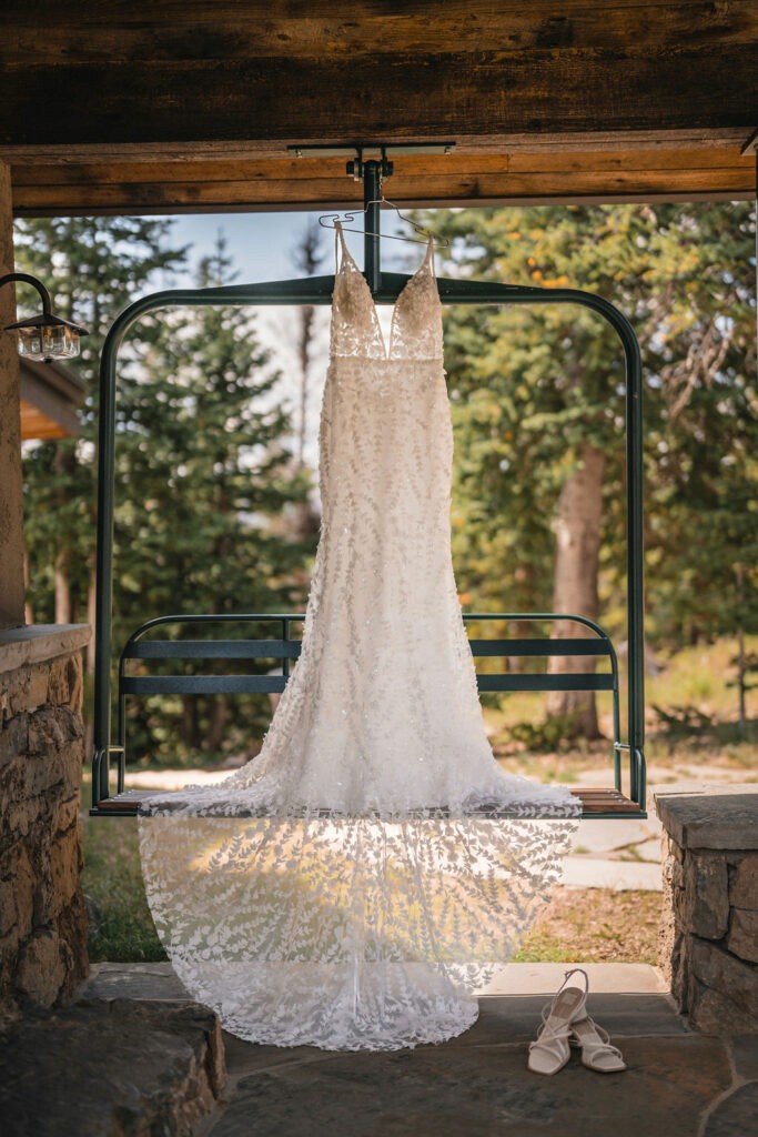 Wedding dress hanging outdoors at Smith Cabin Aspen wedding with mountain cabin backdrop