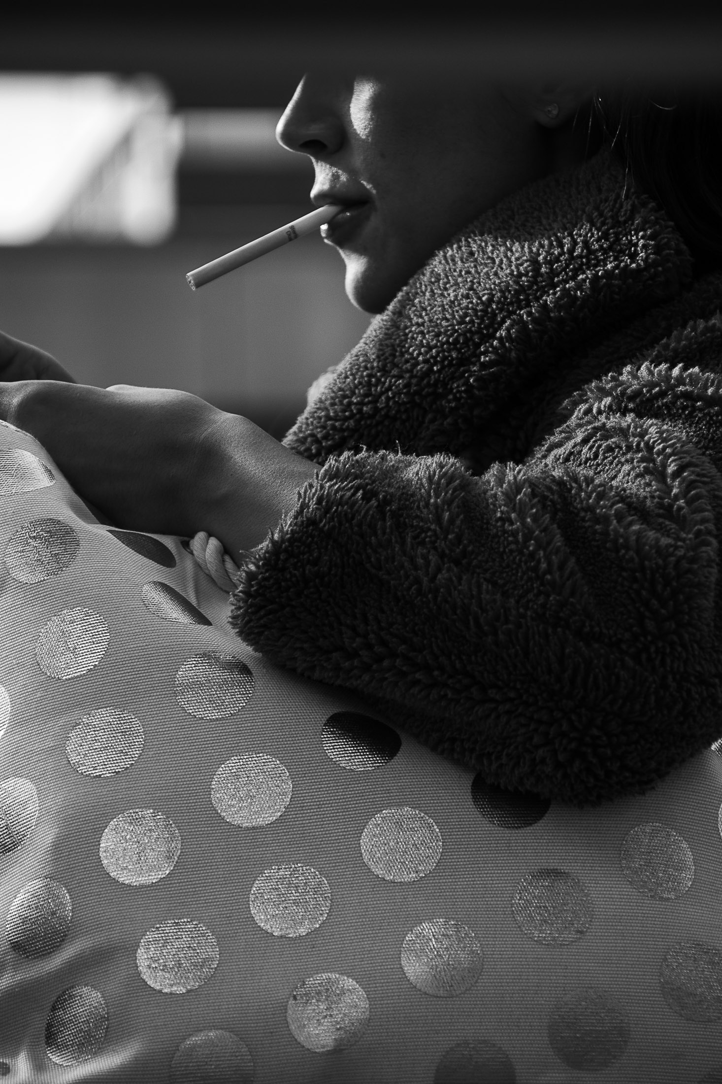 Black and white cinematic portrait of a woman smoking by a window in soft natural light