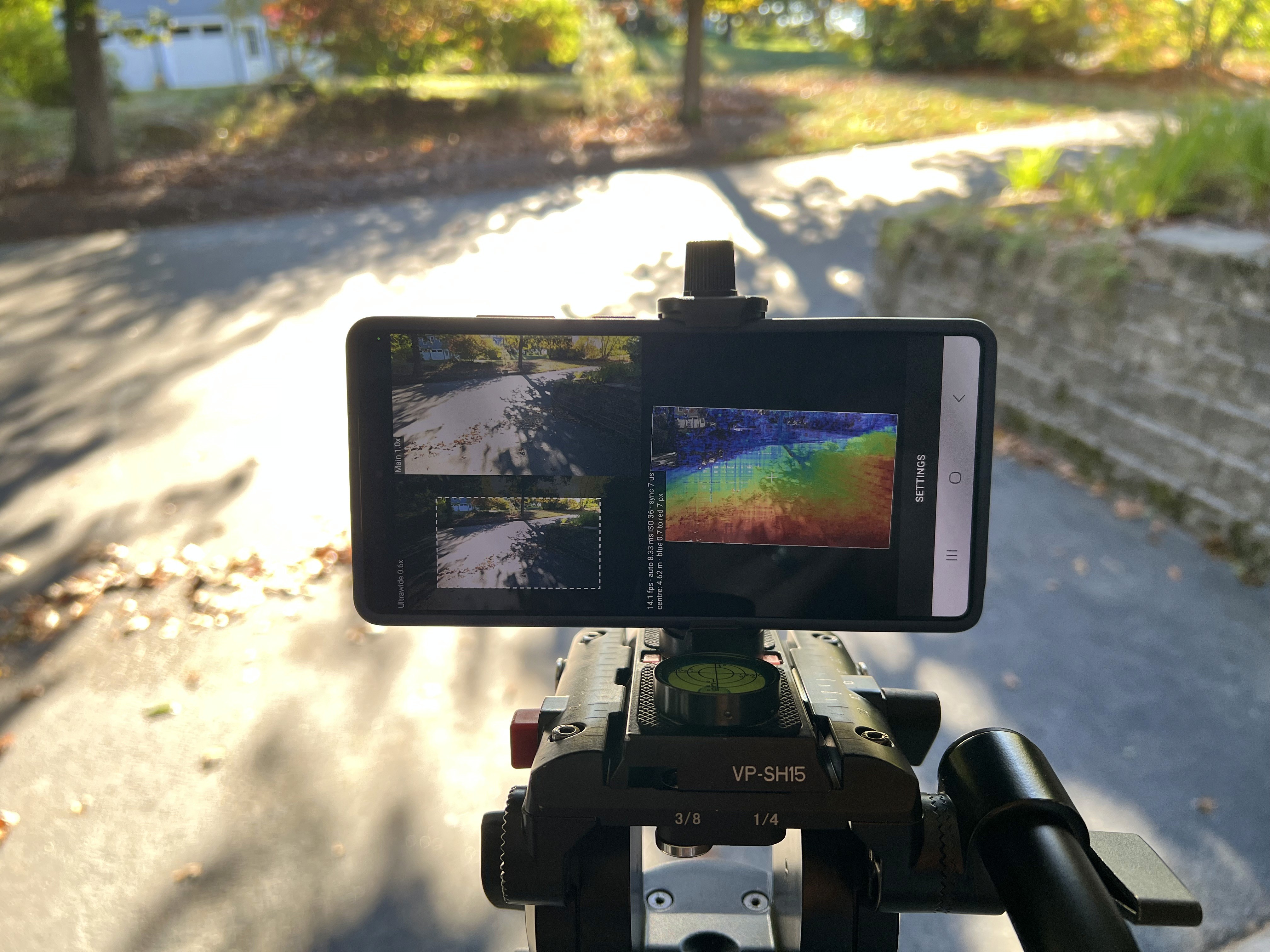 Phone on a tripod running Hammerhead Mobile, showing a color depth map of the curved driveway and stone wall in front of it