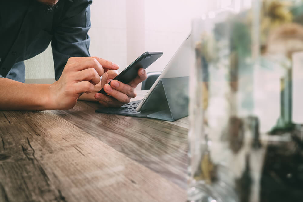 Person using smartphone and tablet on a desk