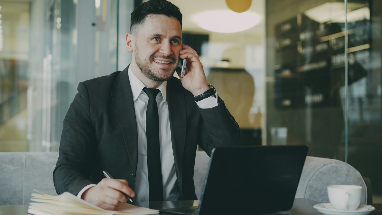 Man in suit talking on phone at laptop