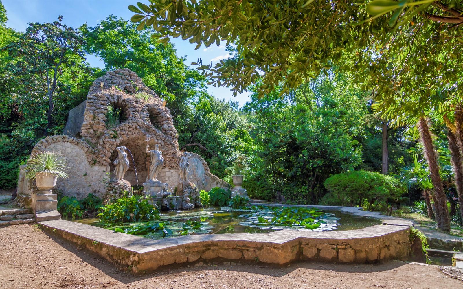 Stone grotto with statues and pond in lush garden, Game of Thrones driving tour location.