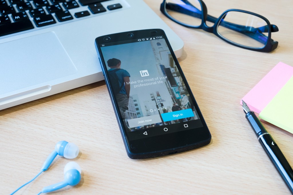 a black phone on a wooden desk surrounded by office supplies