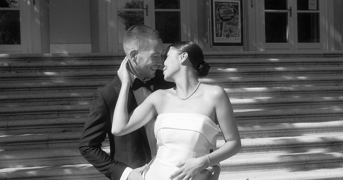 Newly wedded couple standing infront of old stone steps sharing a kiss