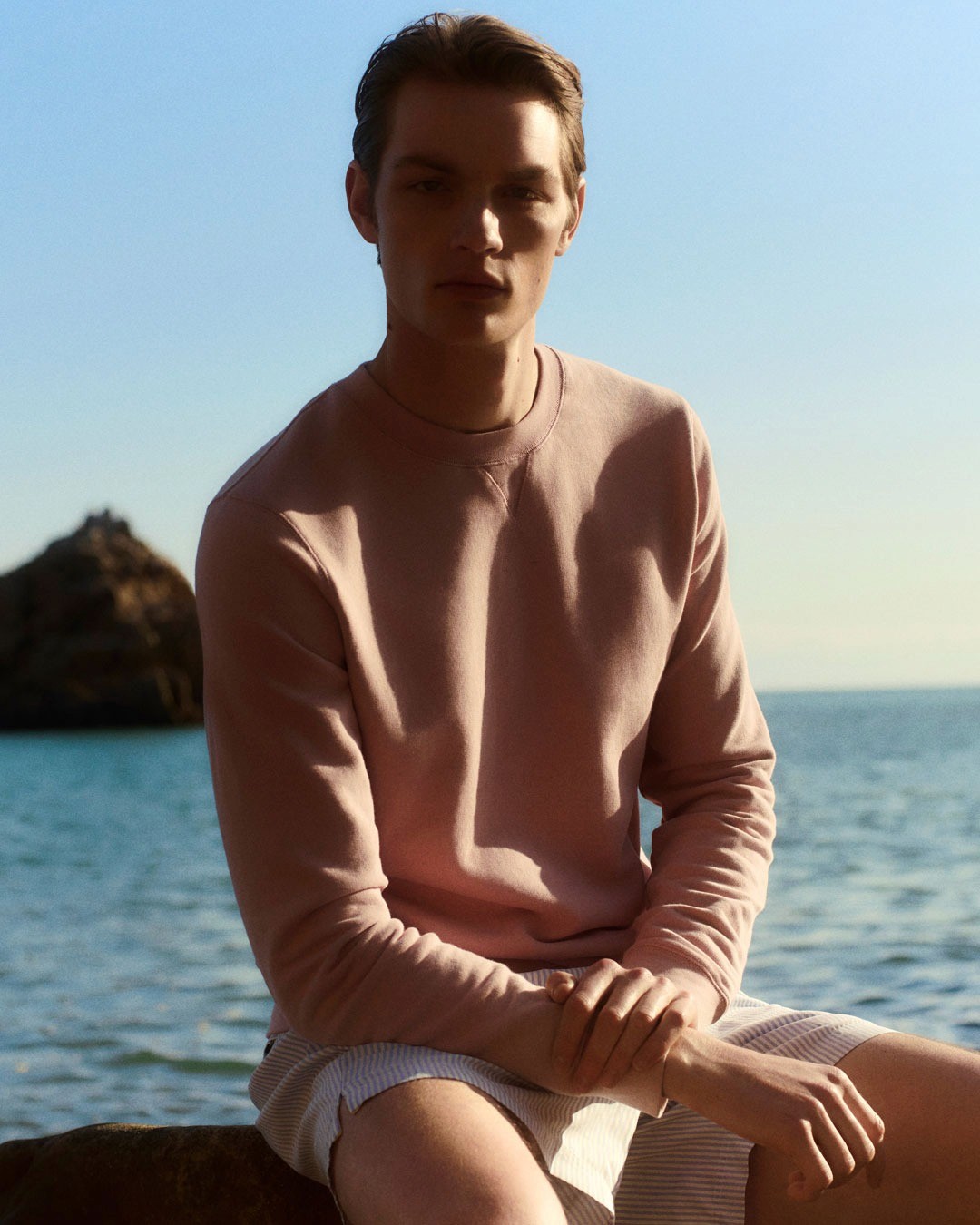 Un mannequin porte en bord demer une maille fine rose Sunspel