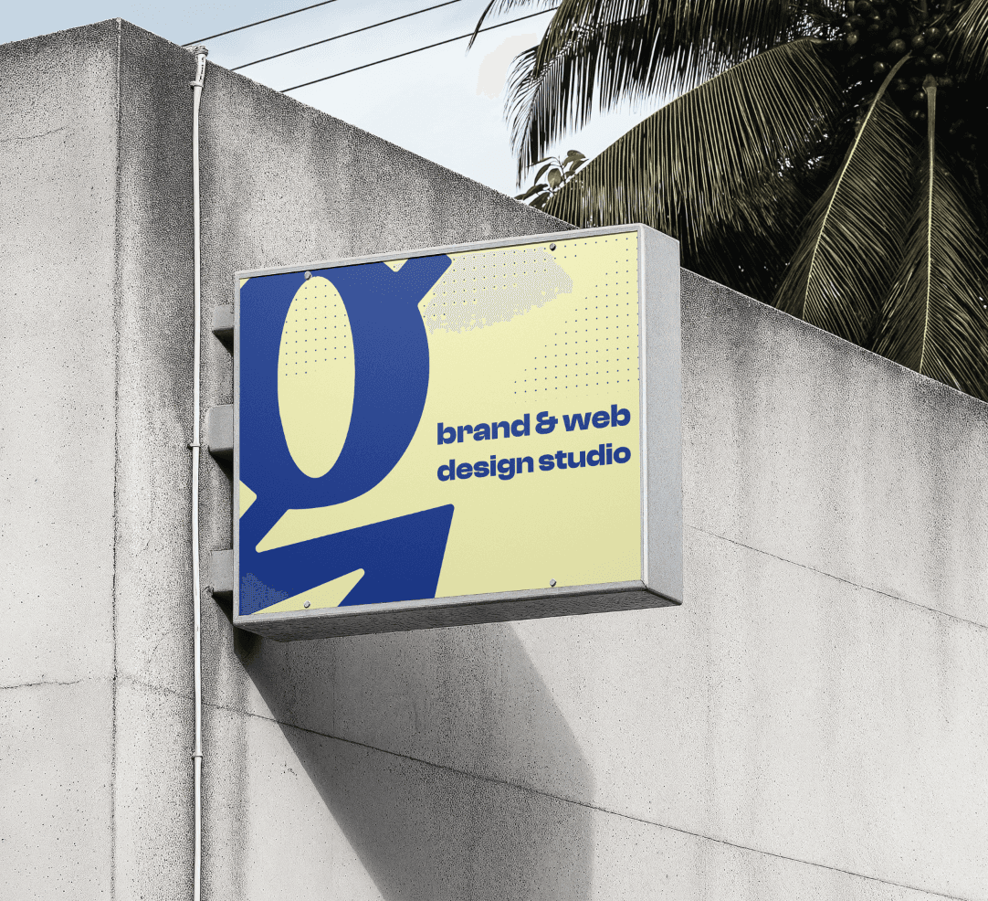 A sign on a gray concrete wall that shows the dark blue brand mark of Re:ignite and that says brand and web design studio on a light yellow color