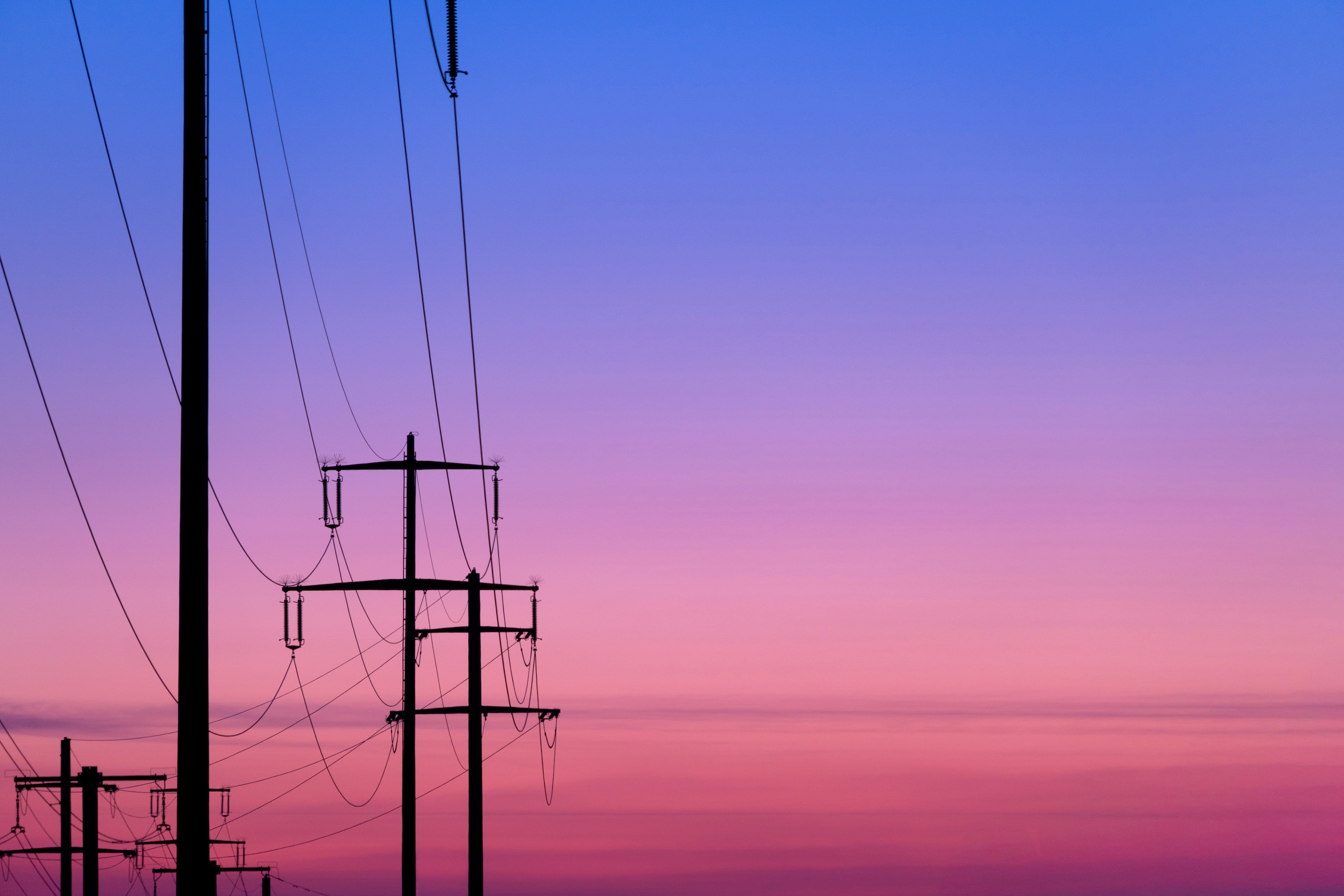Power lines silhouetted against a colorful sunset sky