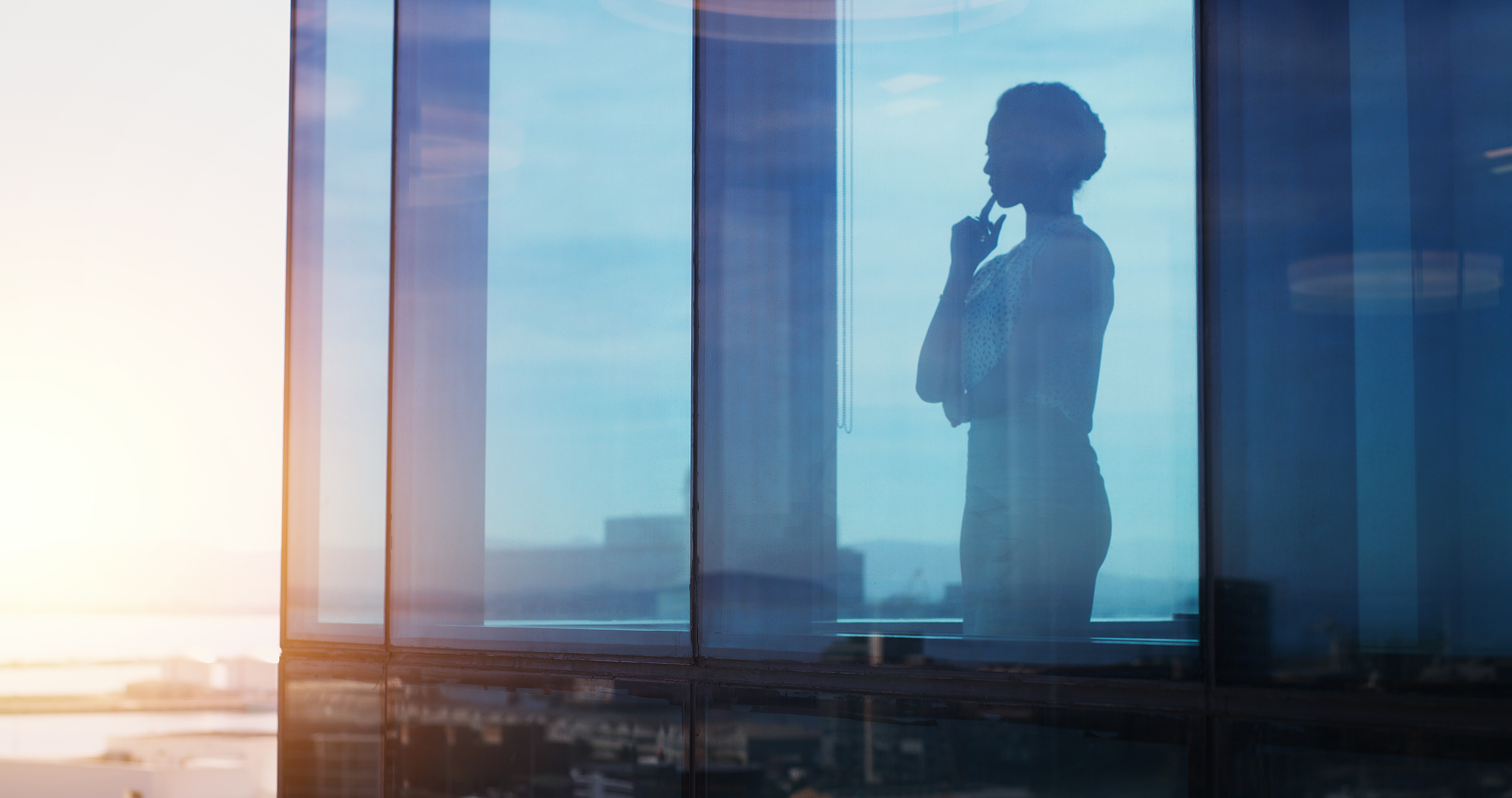 businesswoman looking thoughtful while looking out a window.