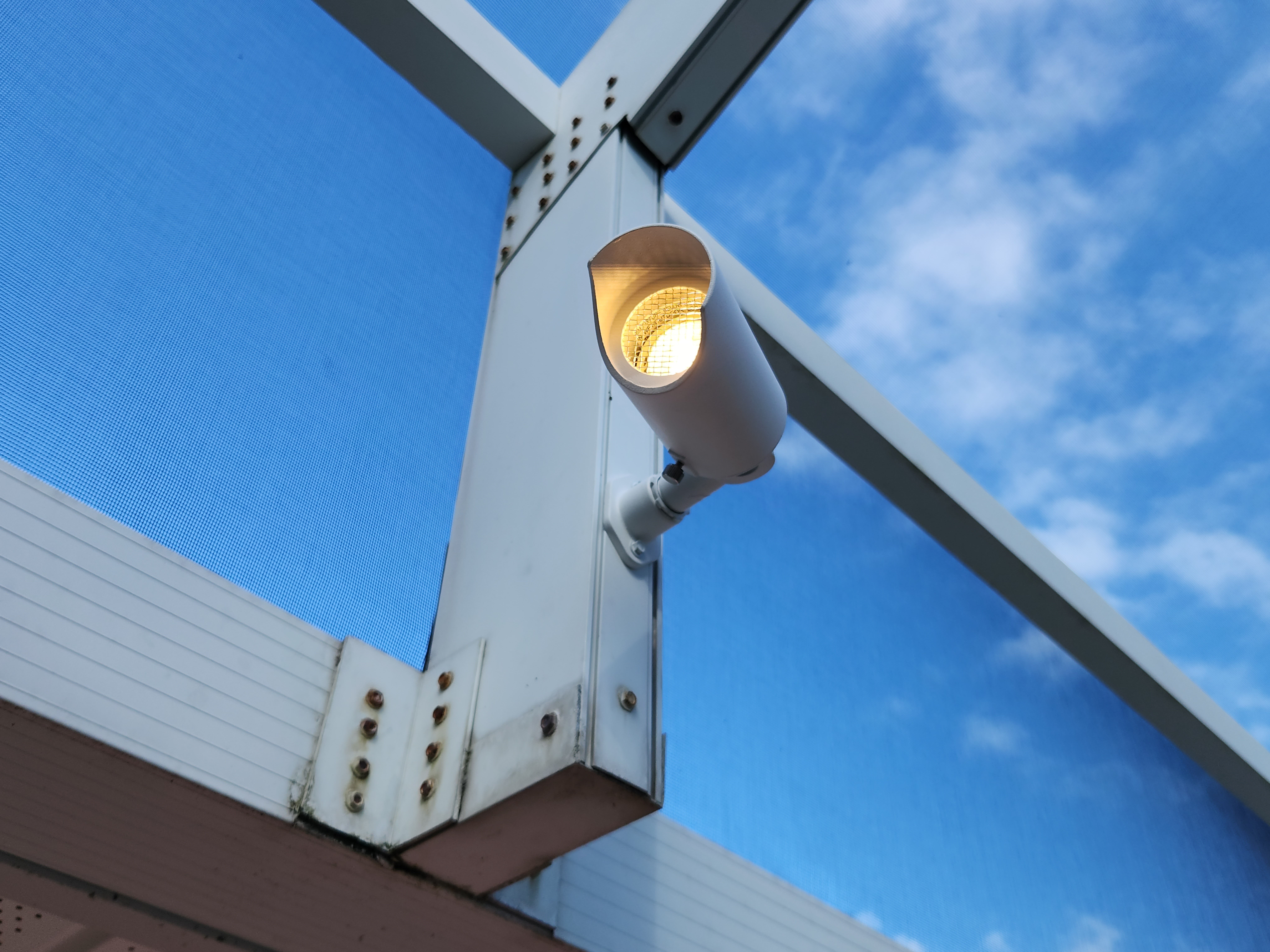Close-up of professional outdoor lighting fixture mounted on pool enclosure frame
