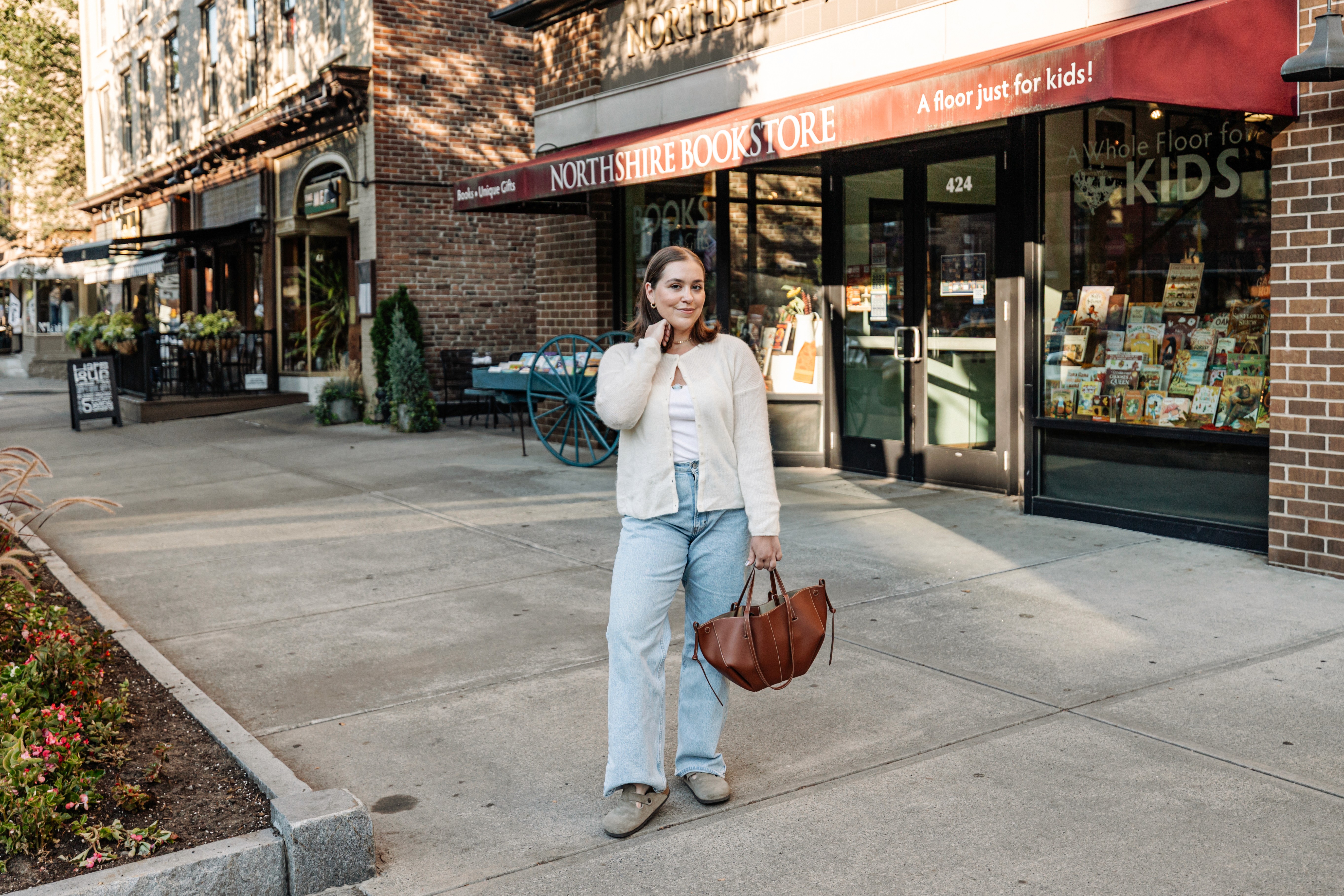 Stylish influencer on Broadway in downtown Saratoga Springs, hands in her hair, looking directly at the camera in a chic fall outfit — bold editorial lifestyle and content creator photography by Lizz Spano Photography, Saratoga Springs lifestyle photographer.