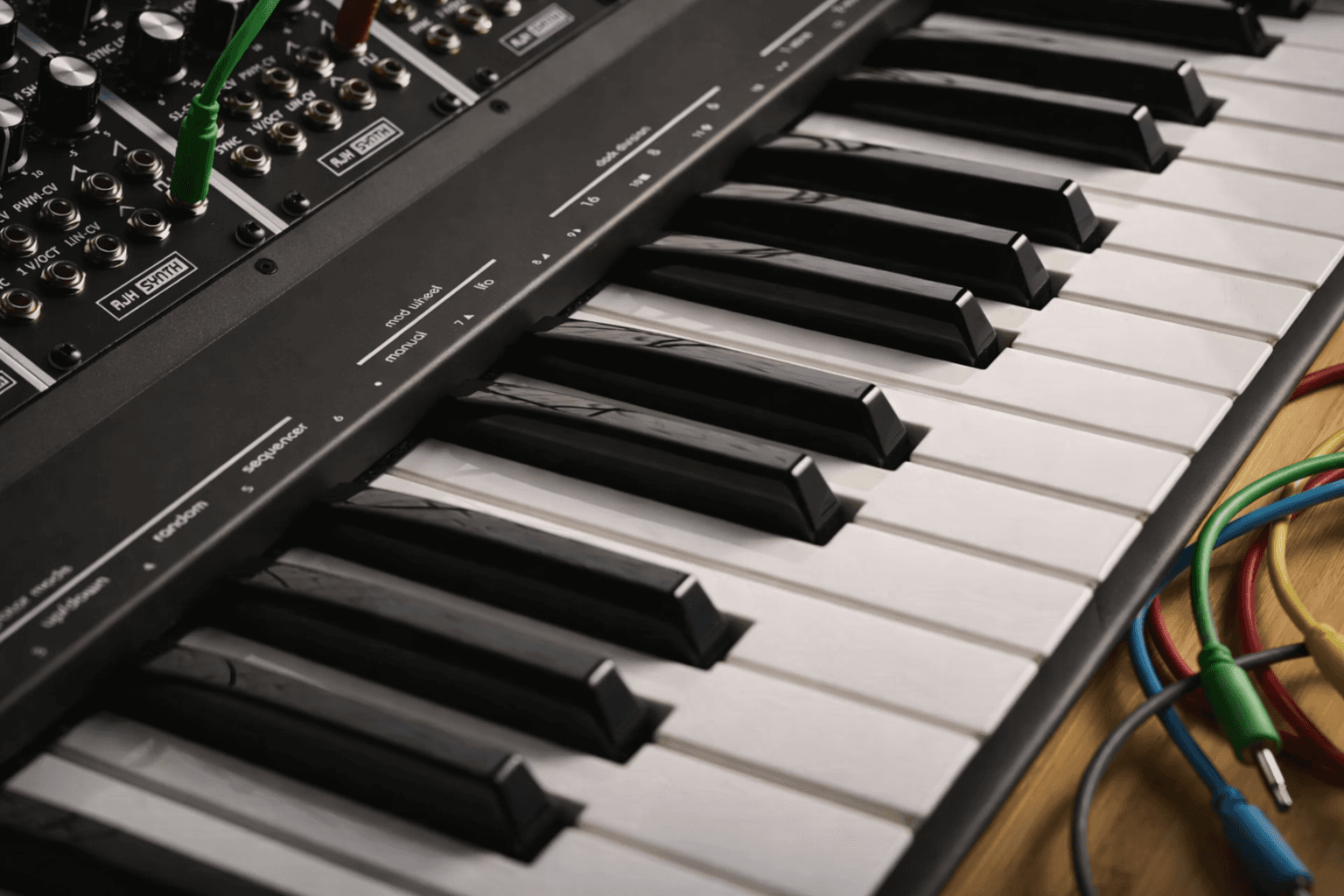 Analog synthesizer keyboard with patch cables, close-up view in a music production setup