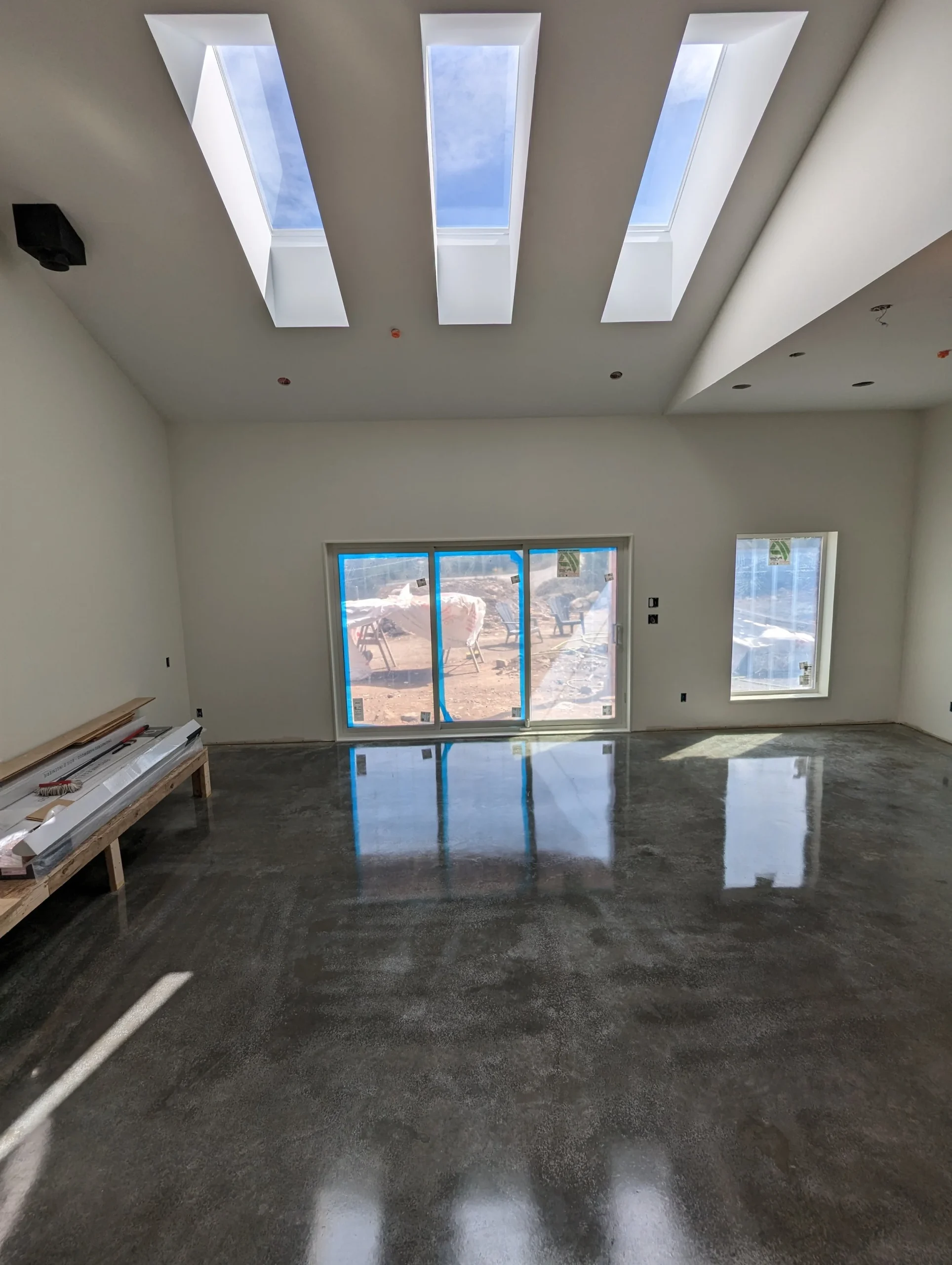 Modern two-story home with large glass windows, warmly lit interiors, and a balcony. Surrounded by trees and a manicured lawn at dusk. Cozy ambiance.