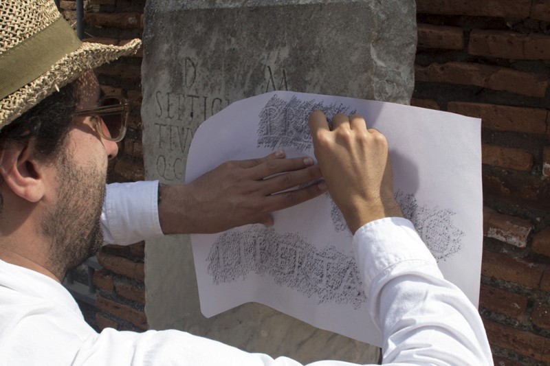 man tracing type on paper